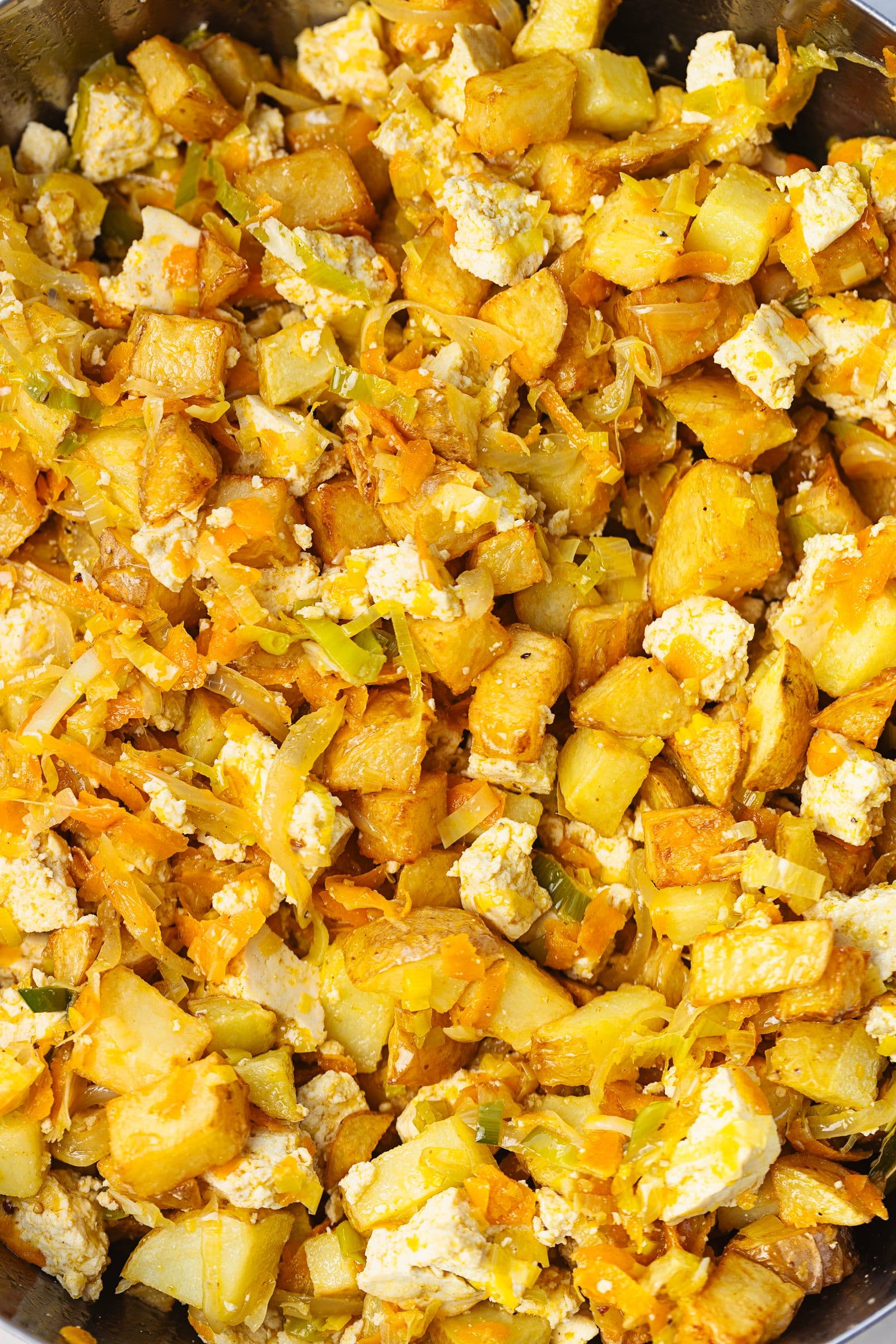 Combined mixture of tofu, fried potatoes and vegetables, fully mixed and ready for the baking dish.