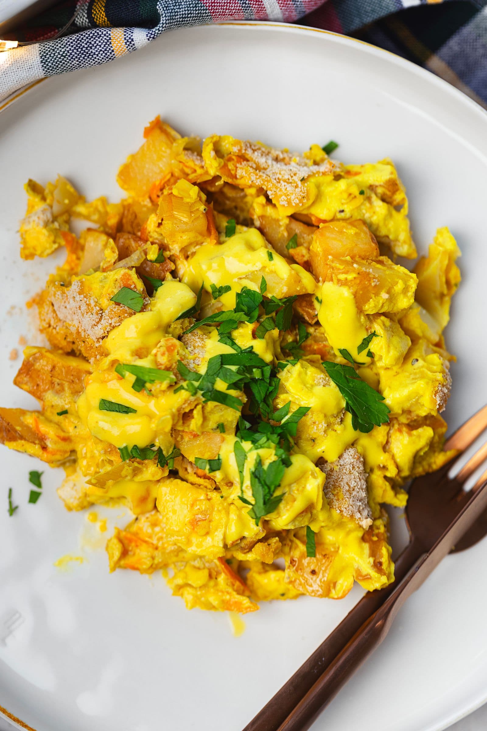 Close-up de uma porção de gratinado com molho cremoso e salsa fresca por cima.