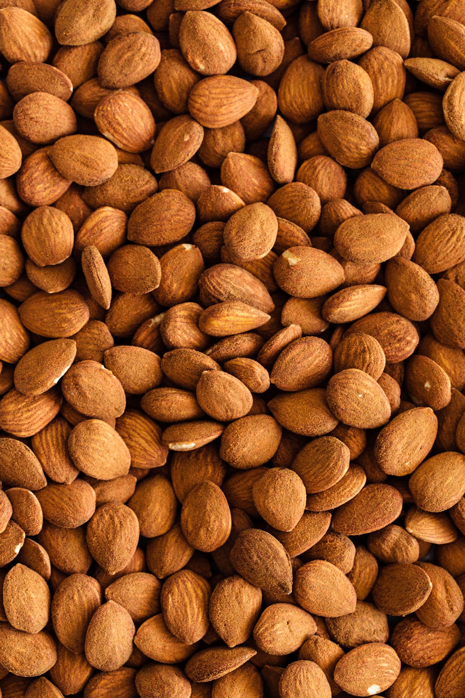 Close-up view of raw almonds with brown skins, spread out evenly.
