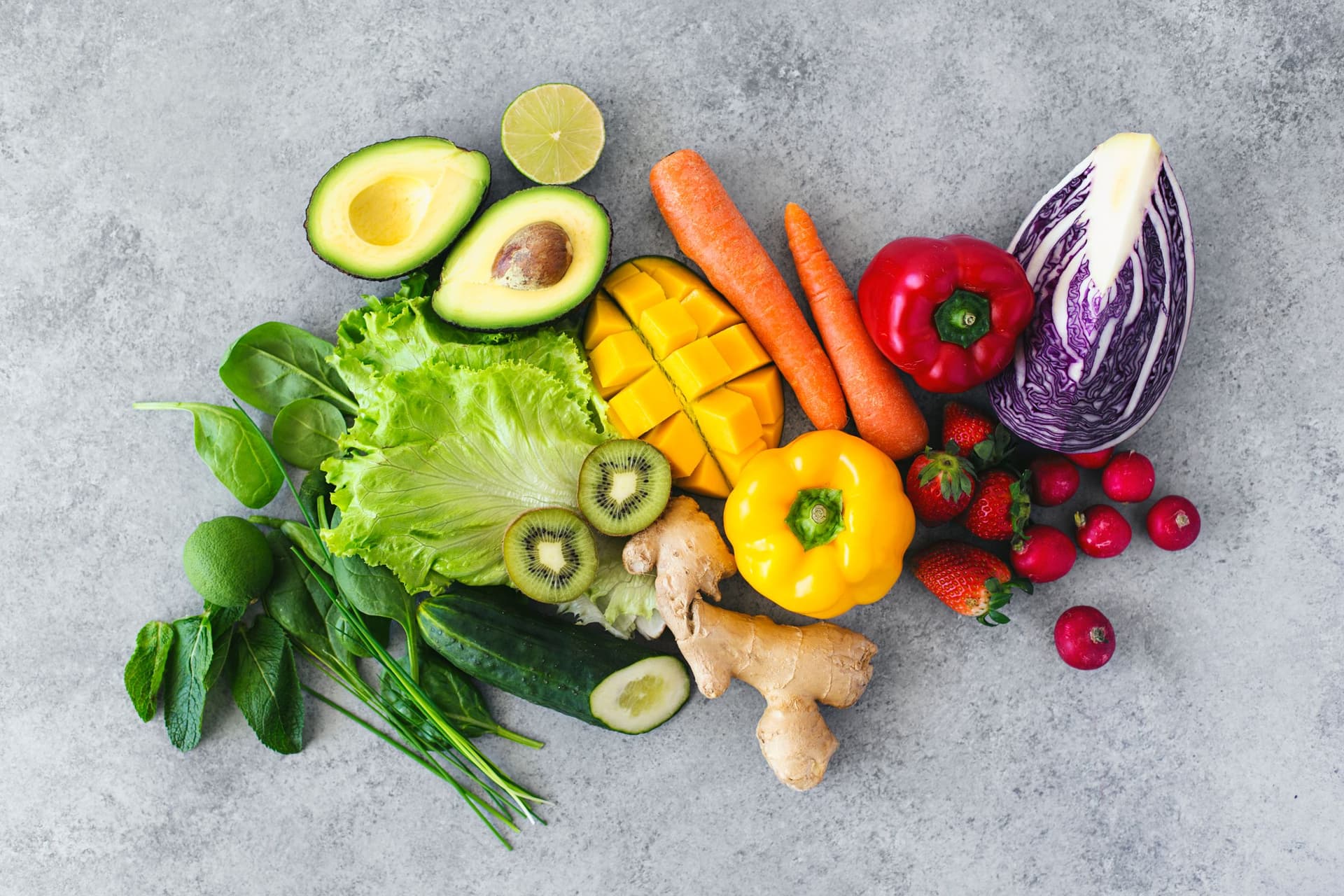 Rainbow of bright vegetables and fruits arranged on a grey background for spring rolls.