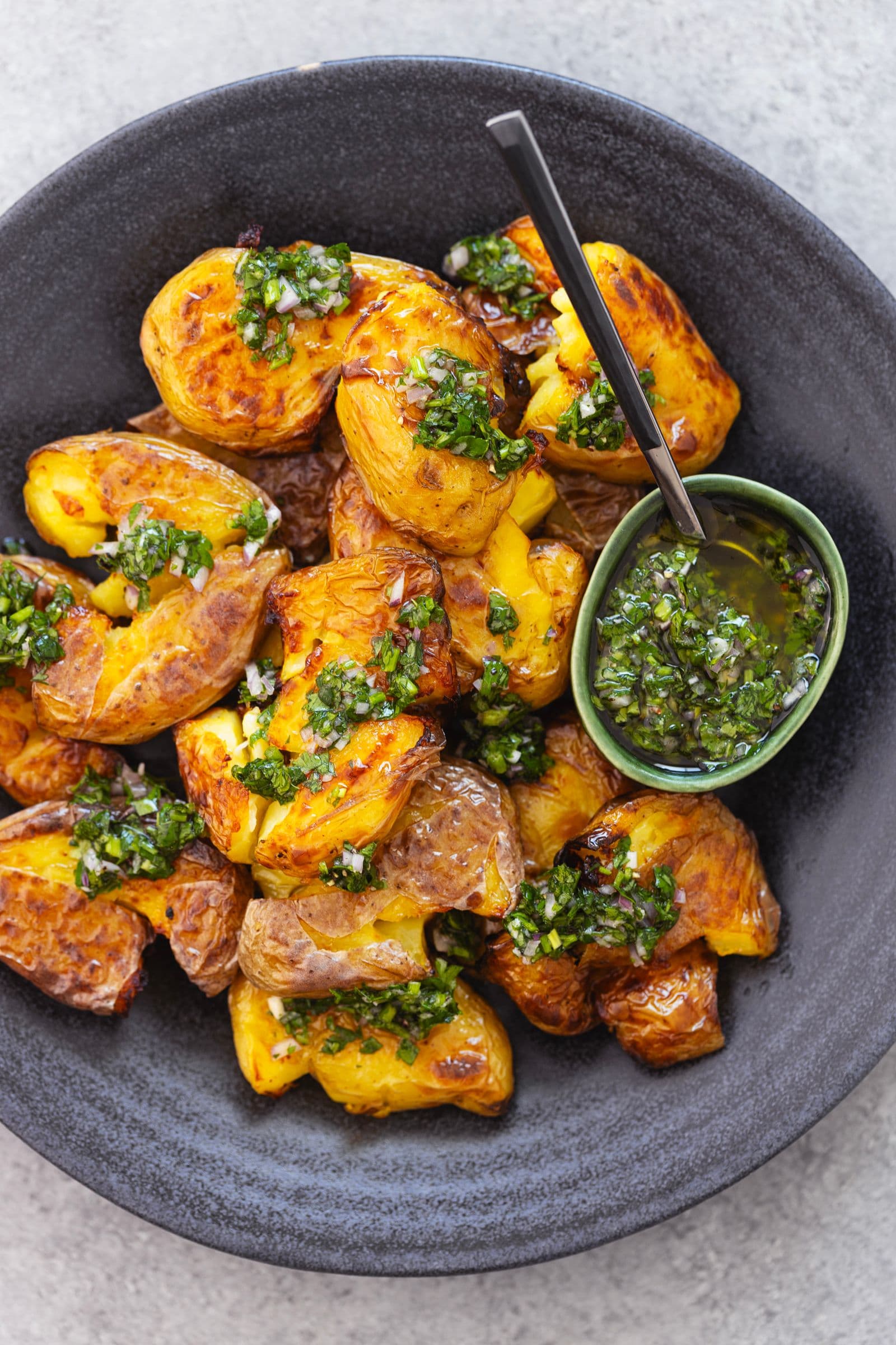 Batatas crocantes com ervas frescas, servidas com molho chimichurri em taça verde