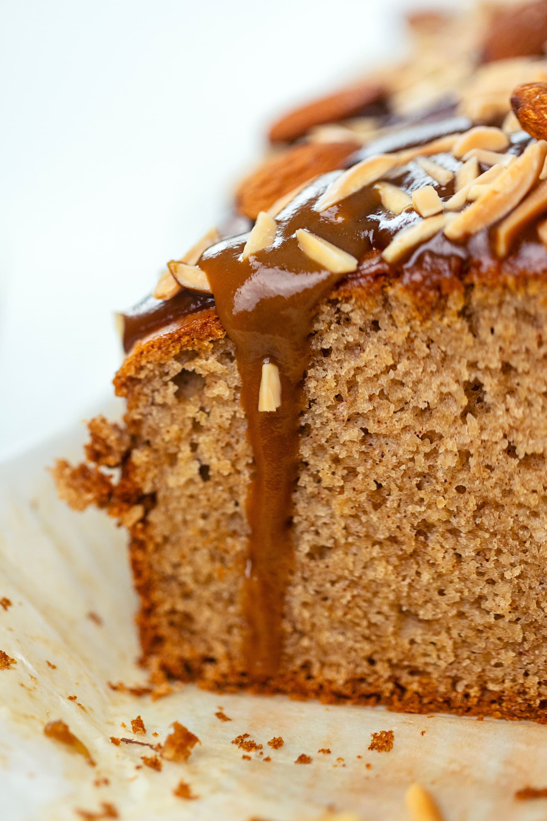Close-up of the almond cake interior showing a spongy crumb with coconut caramel dripping down the side.