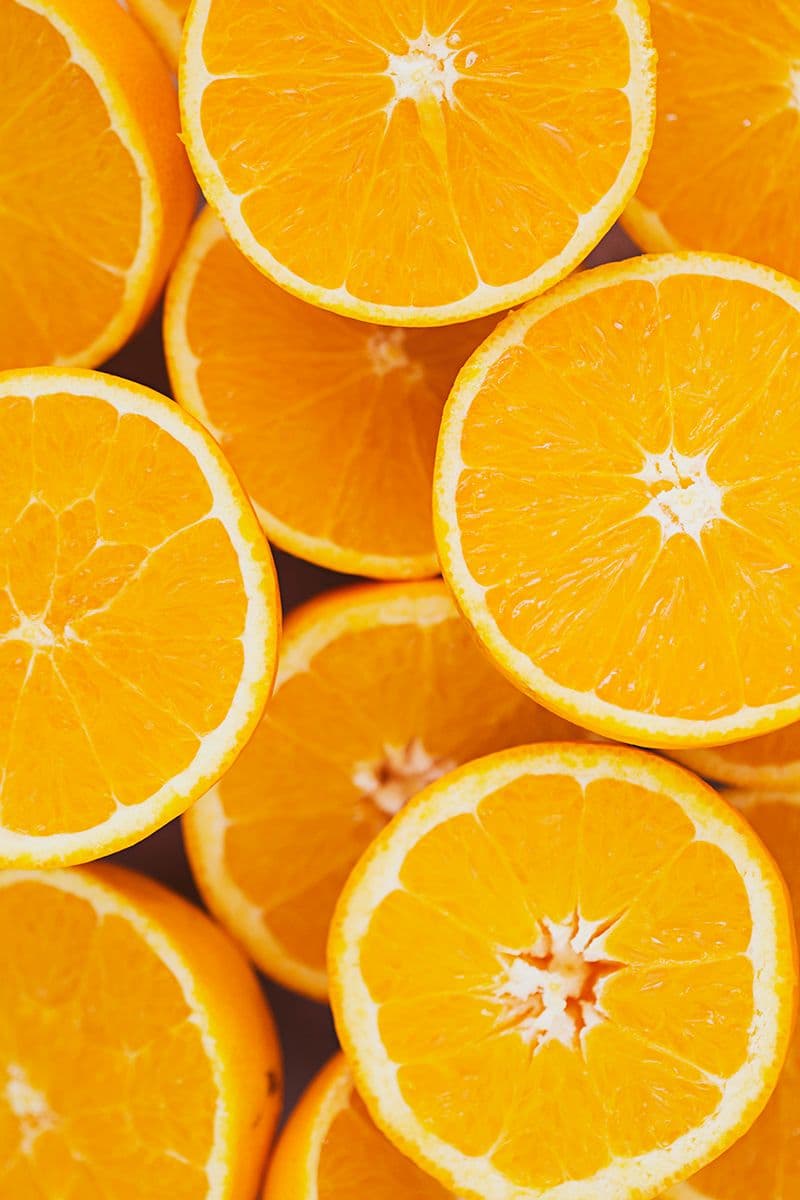 Overhead view of halved oranges arranged in a tight pattern.