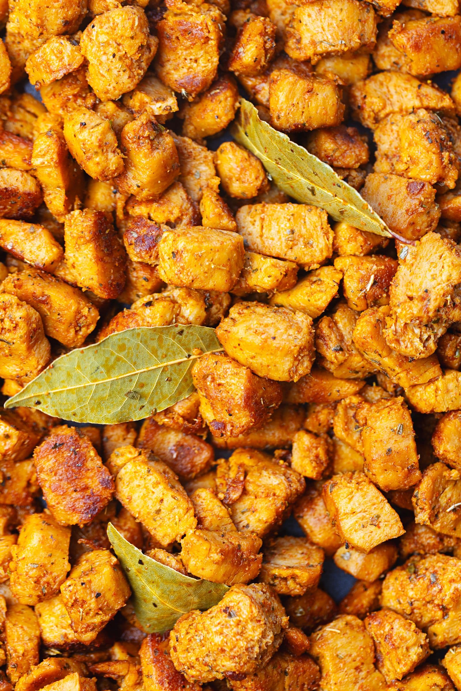 Close-up de nacos de soja caramelizados e fritos com especiarias e folhas de louro numa frigideira escura