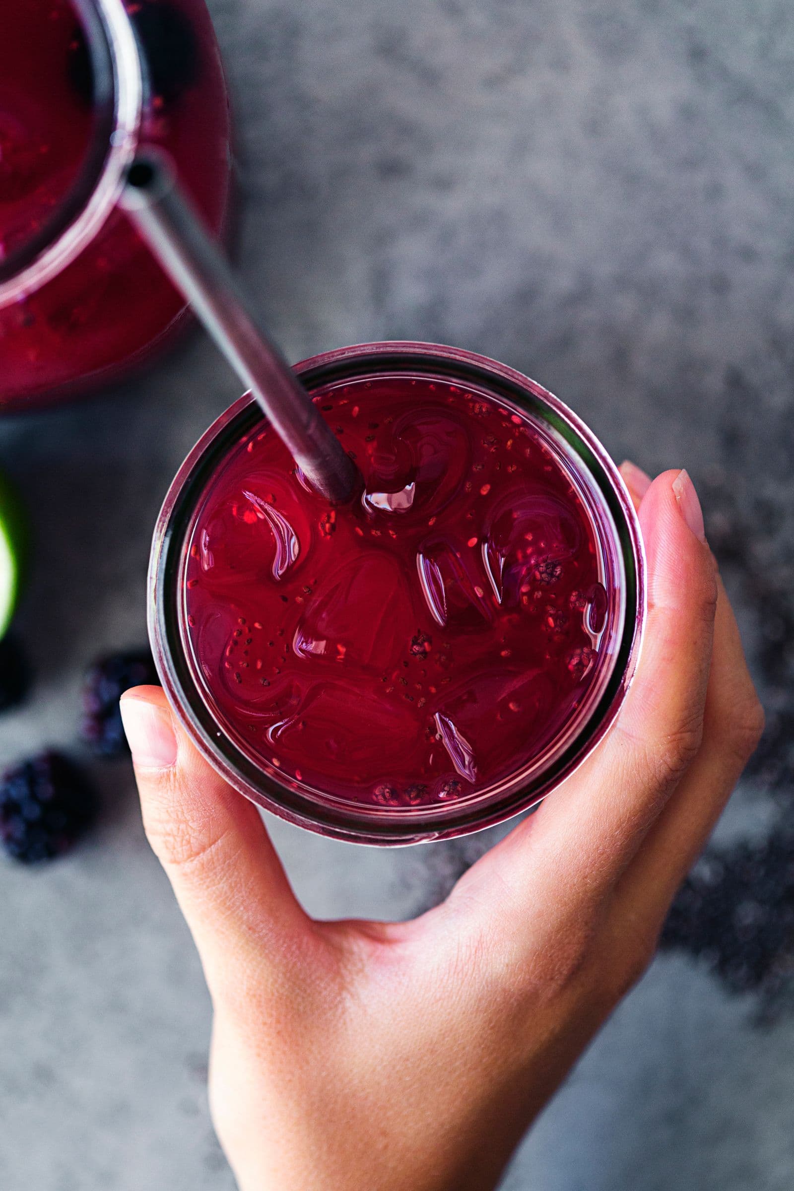 Overhead shot of hand holding a glass of blackberry and lime chia fresca.