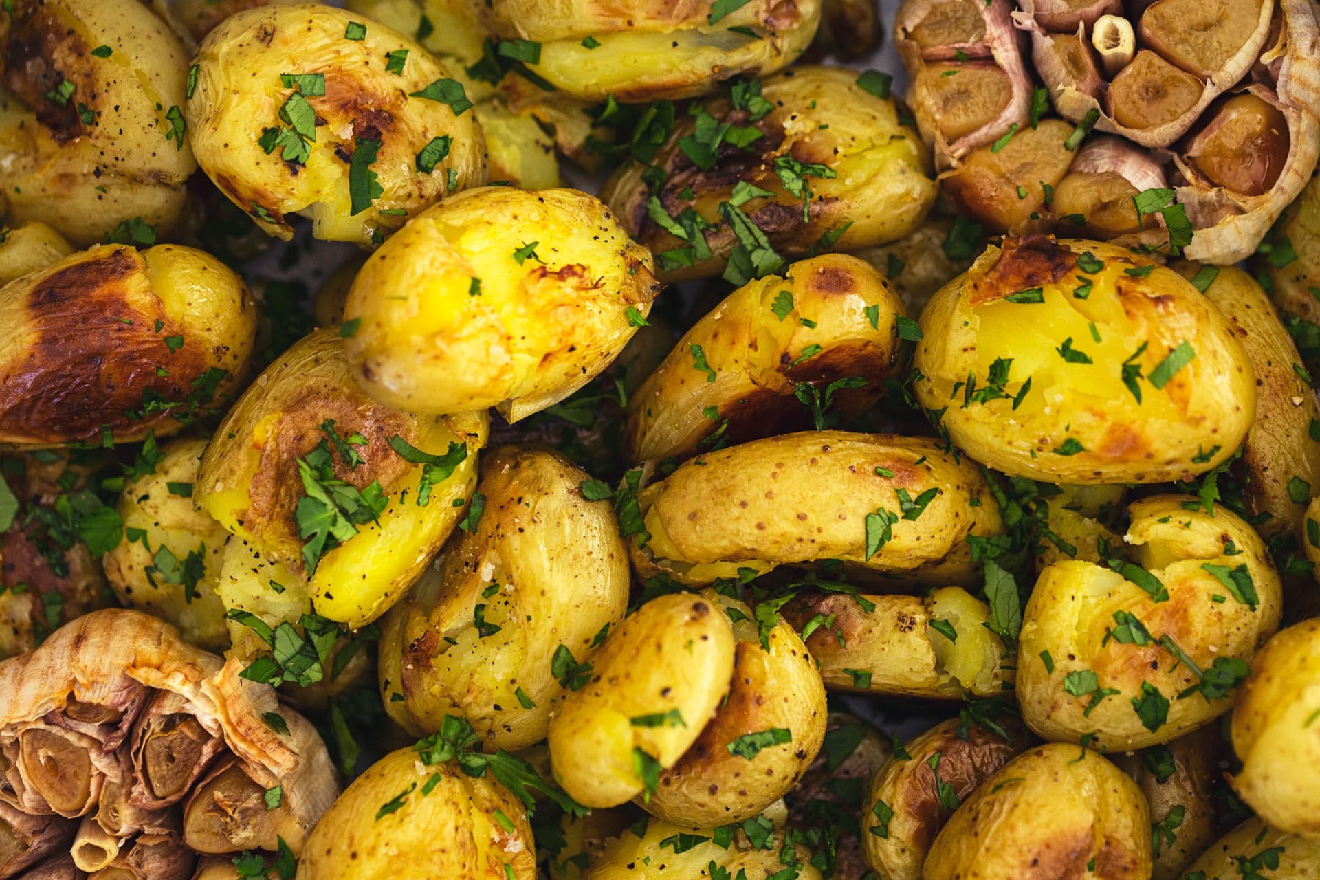 Batatinhas assadas com salsa fresca e alho confitado, brilhantes com azeite.