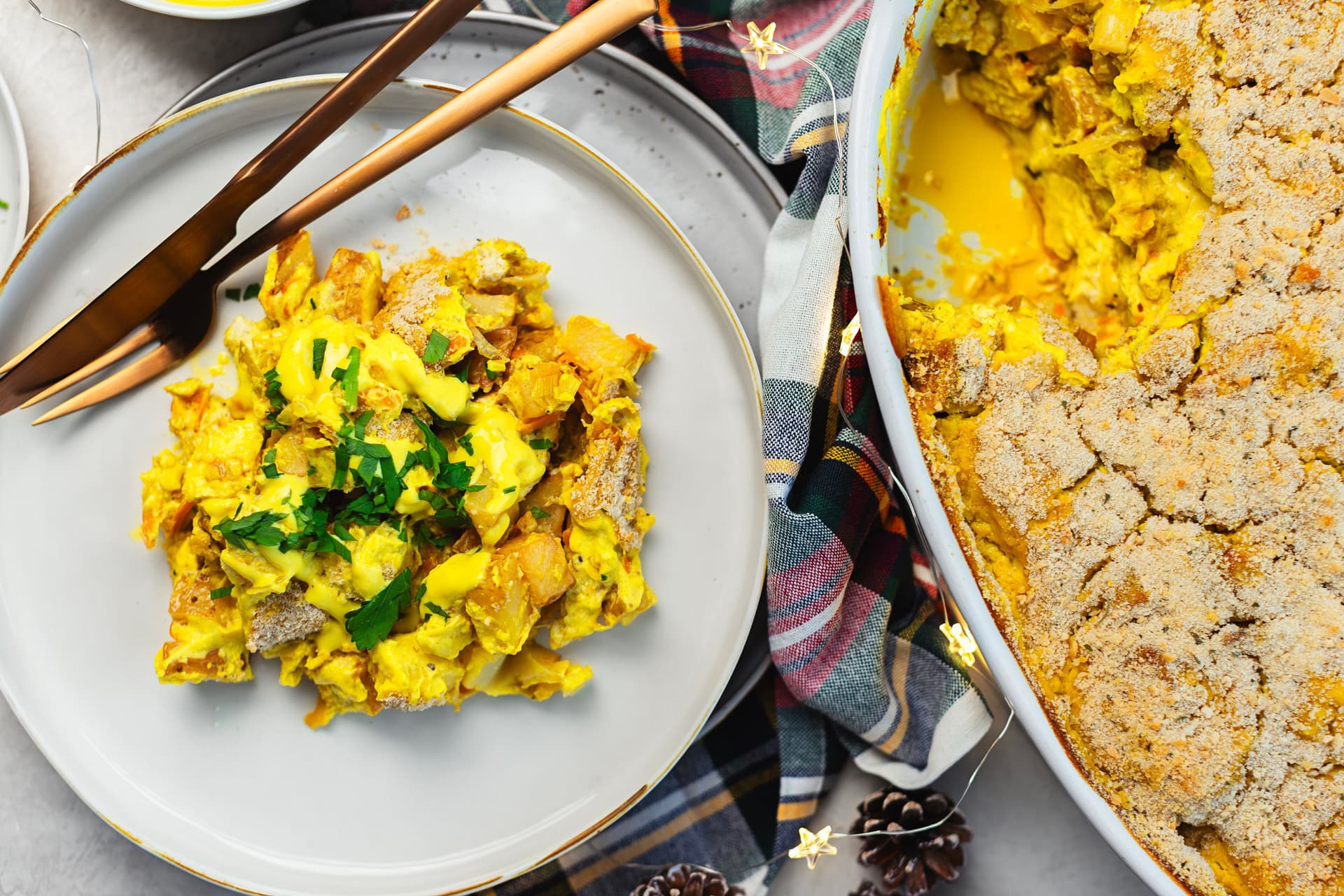 Prato com gratinado servido, talheres e a travessa grande ao lado