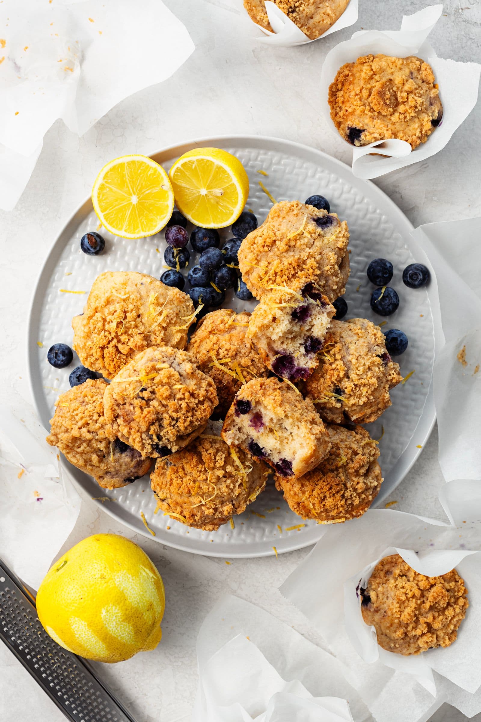 Prato com queques de limão e mirtilos com crumble, decorado com mirtilos frescos e limão.