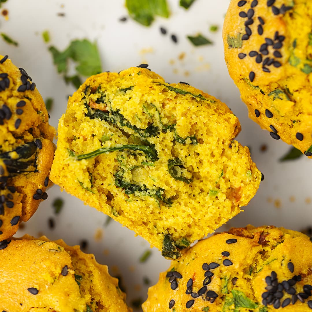 Queque salgado de grão, espinafres e tomate-cereja, cortado ao meio para mostrar o interior.