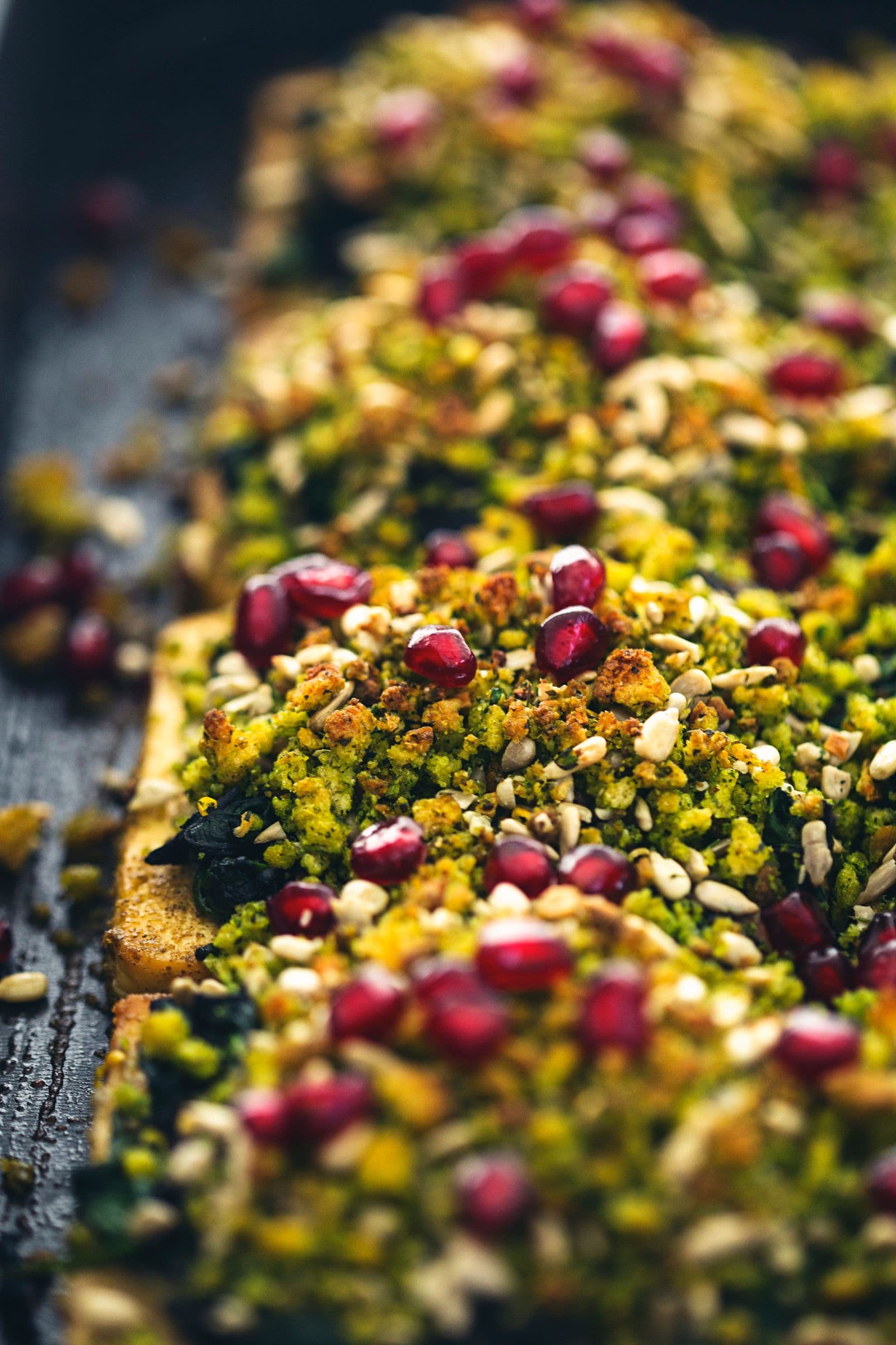 Detailed view of golden tofu roast with cornbread crumble, herbs and pomegranate.