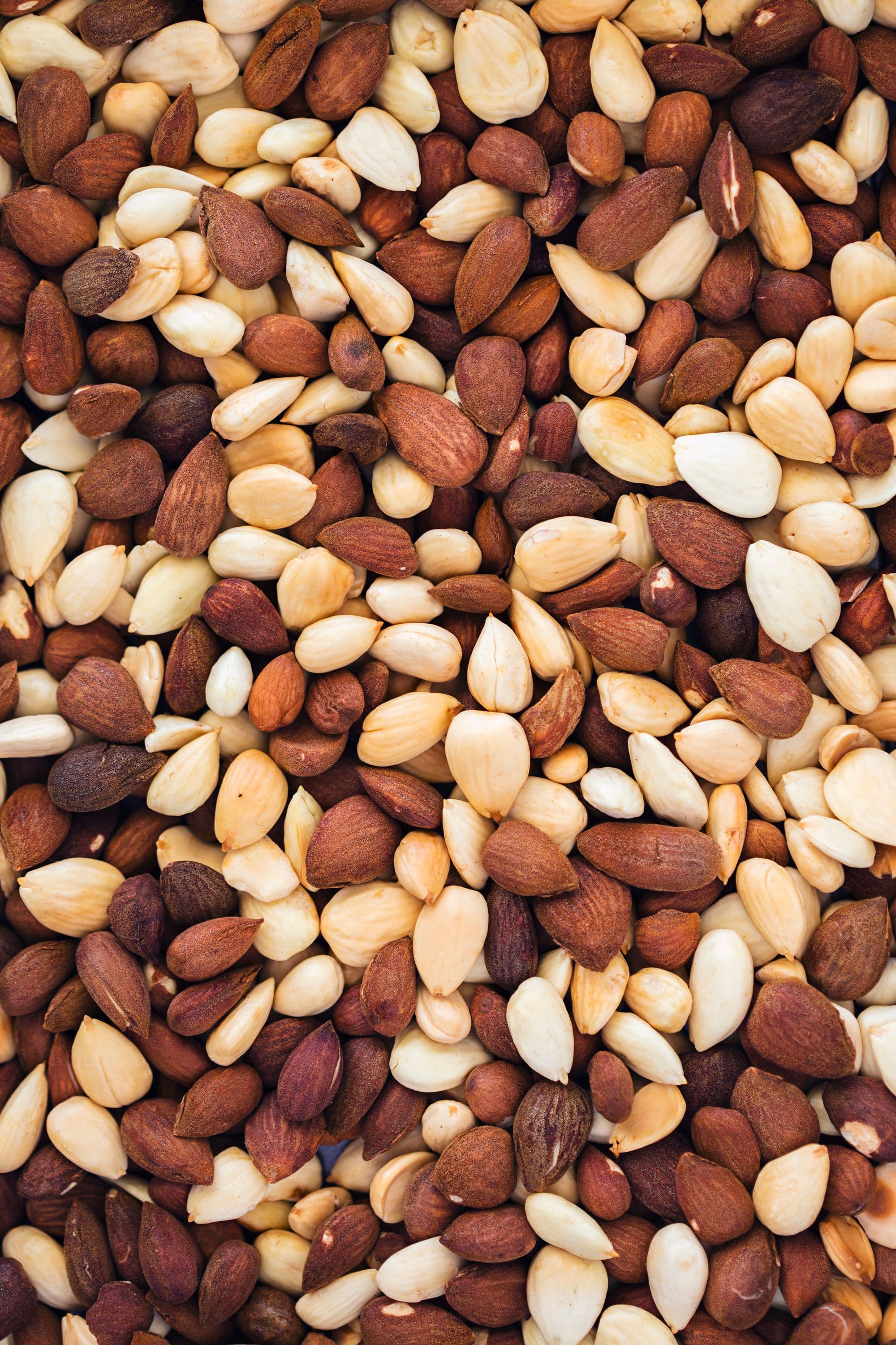 A mix of whole peeled and unpeeled raw almonds.