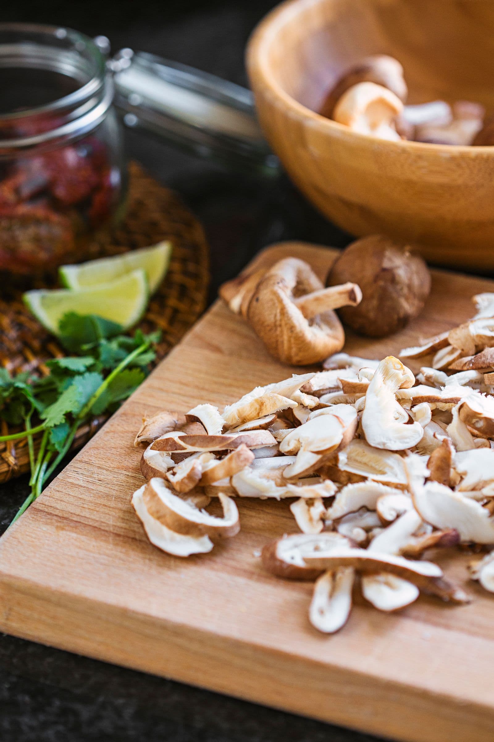 Chopped shiitake mushrooms on a cutting board surrounded by other quesadilla ingredients.