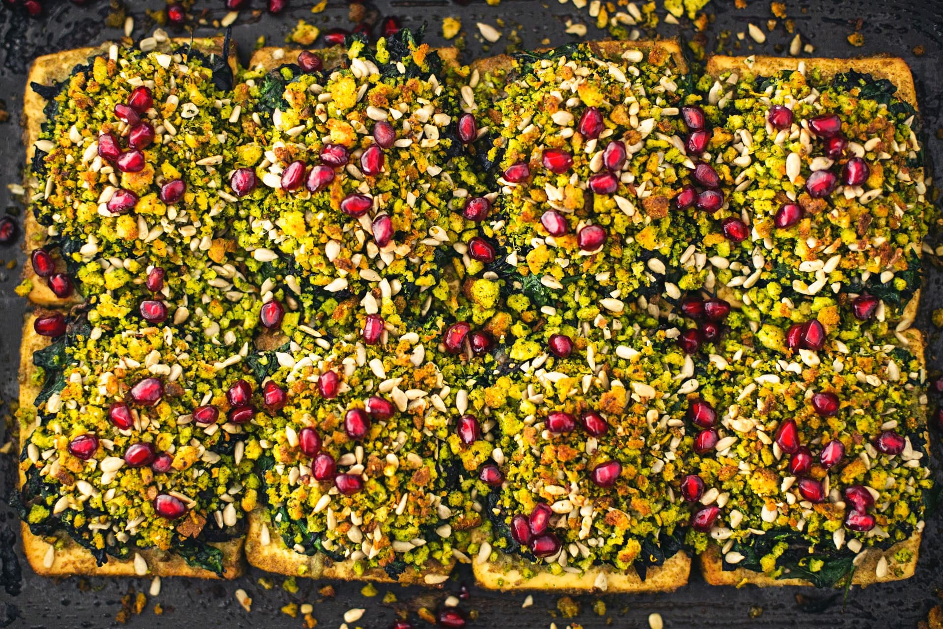 A full tray of tofu roast covered in colorful cornbread crumble with pomegranate seeds.