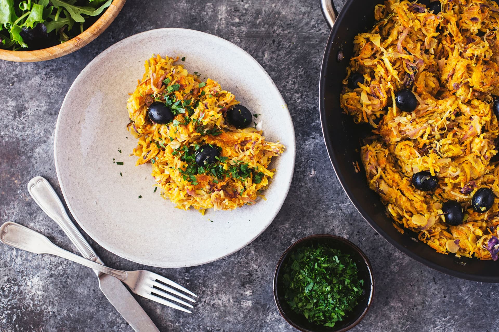 Prato de Vegetais à Brás guarnecido com azeitonas pretas e salsa fresca e servido com salada verde fresca.