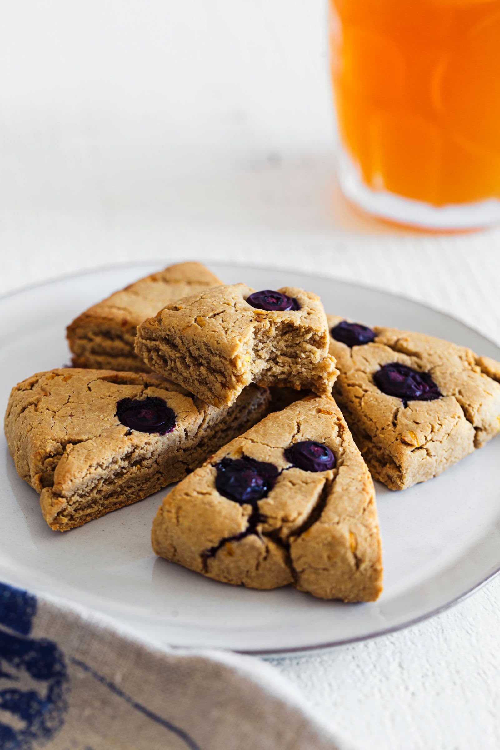 Close-up of golden-brown vegan scones with bursting blueberries on top.