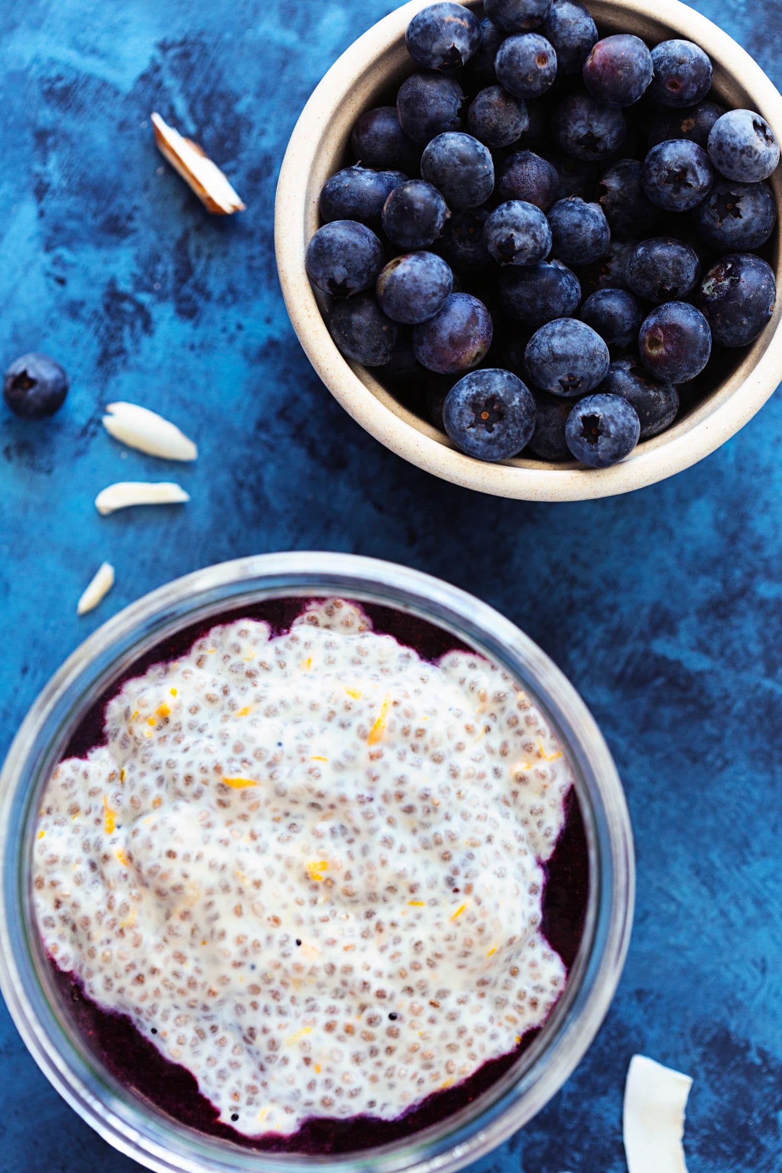 Fresh blueberries in a small bowl next to a jar of chia pudding.