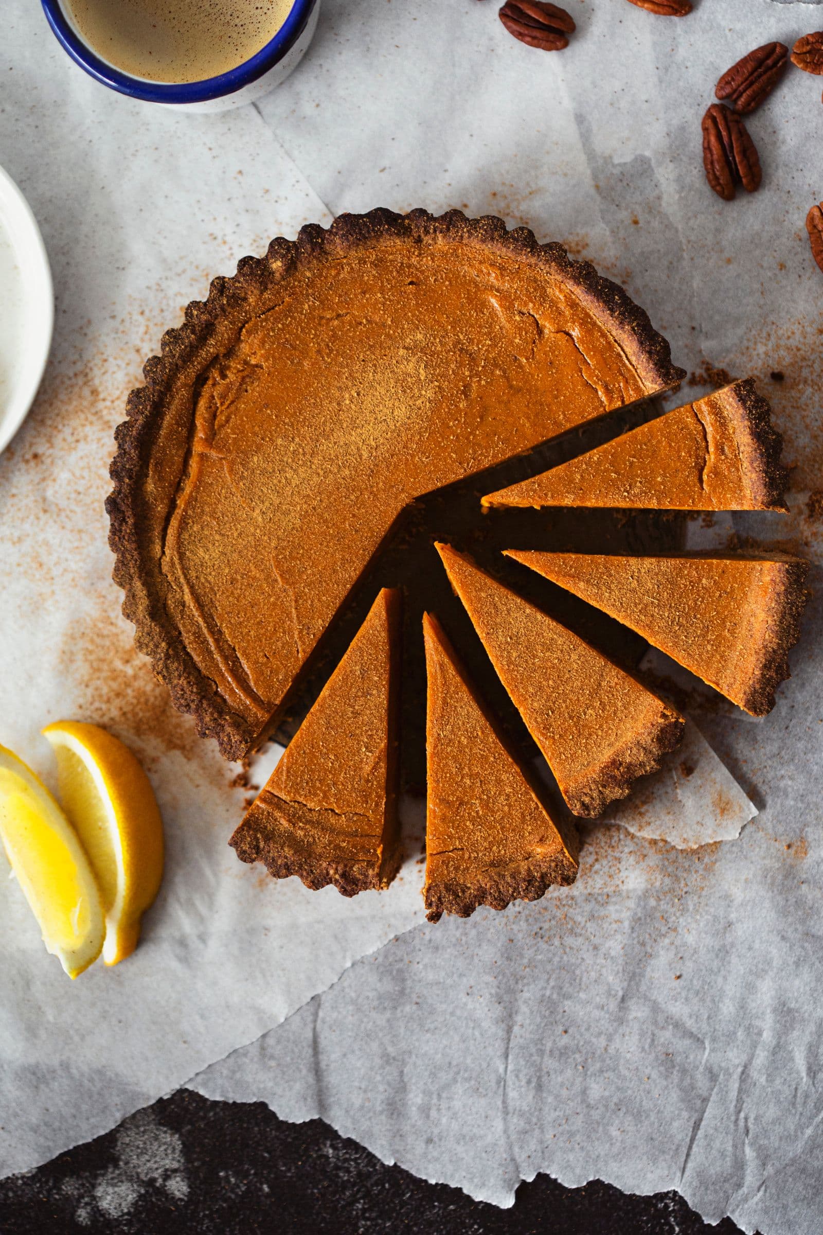 Vista aérea da tarte de batata-doce com várias fatias cortadas, papel vegetal polvilhado com canela.