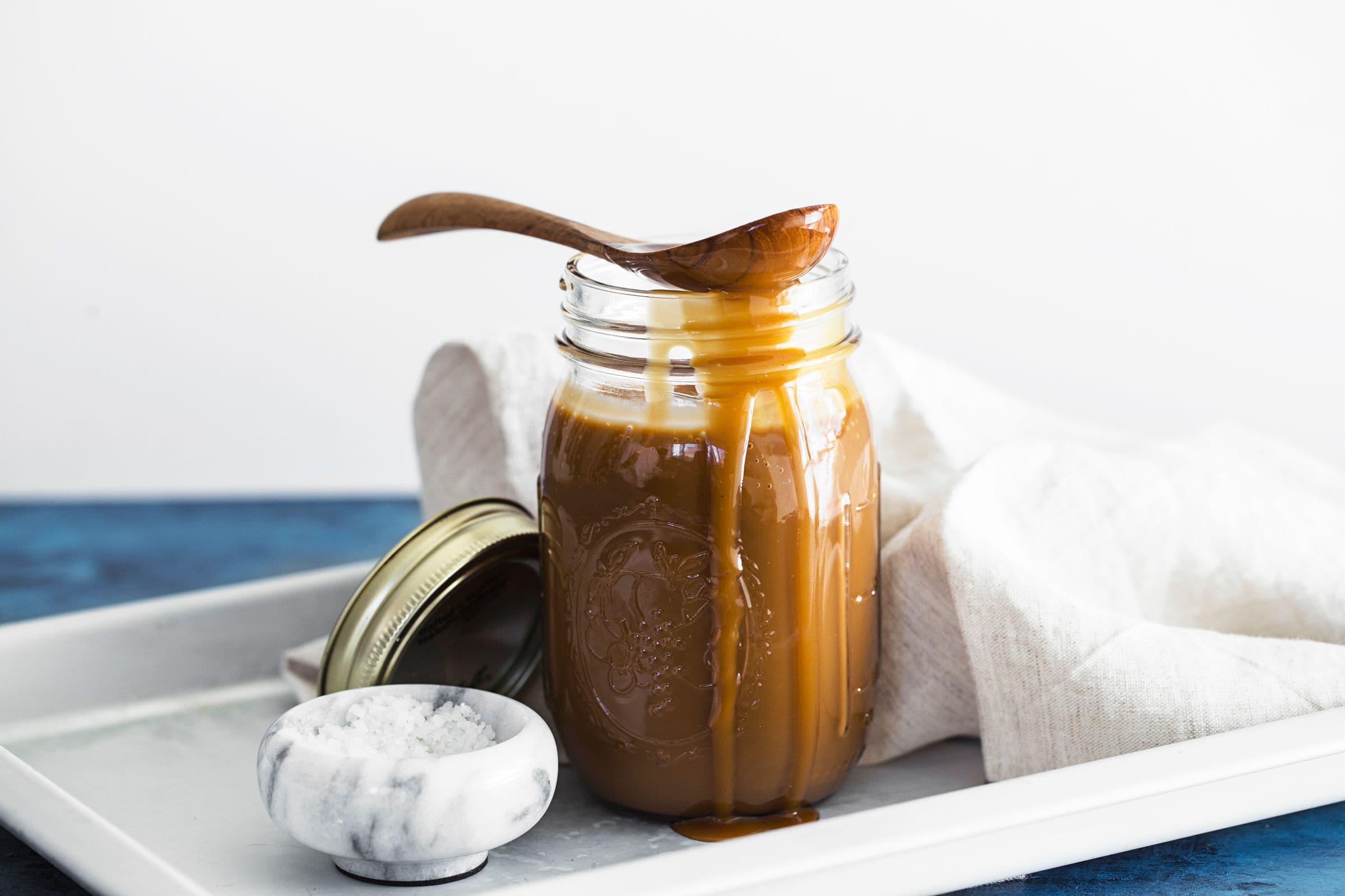 Glass jar with vegan coconut salted caramel dripping down the sides.