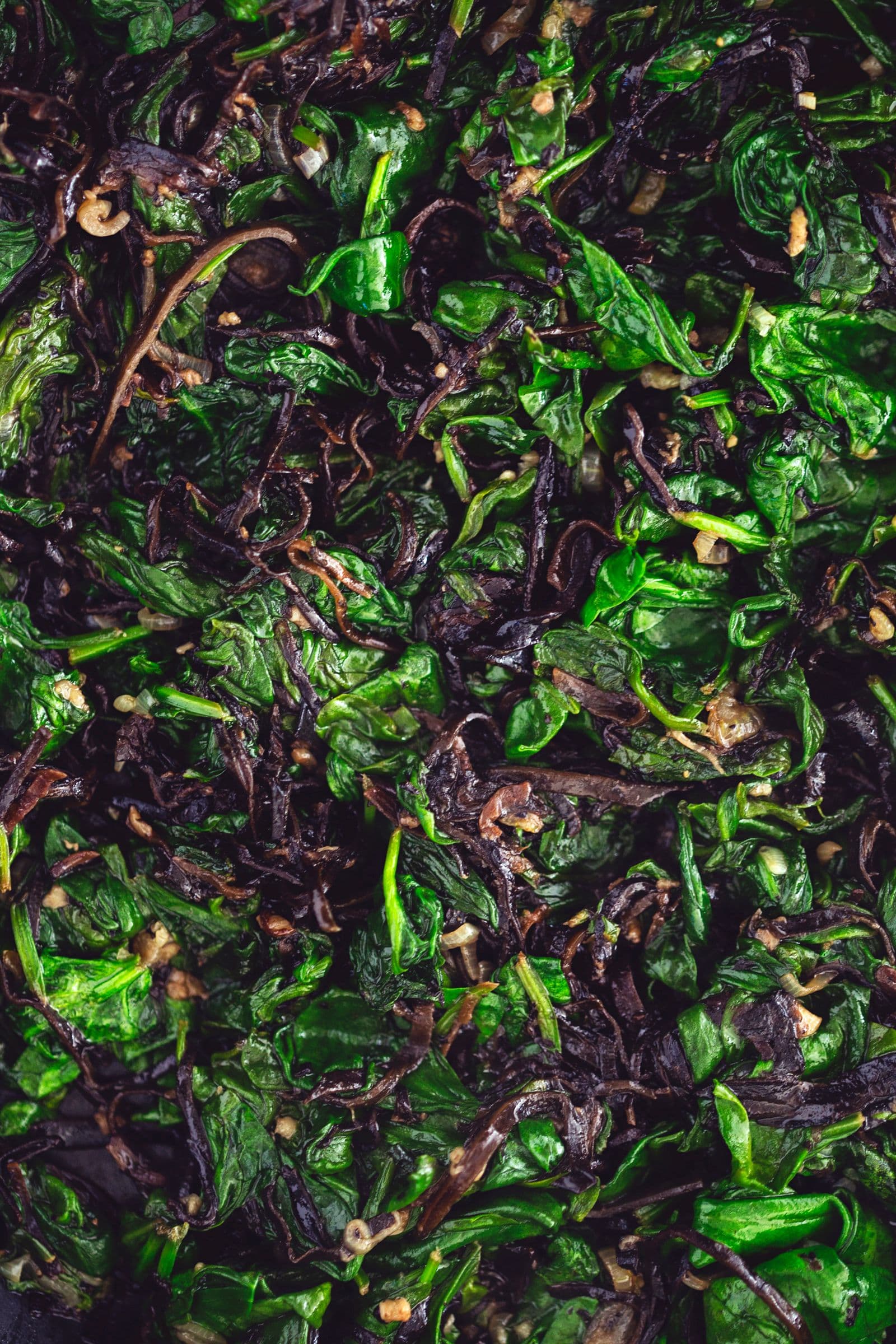 Mistura de espinafres e algas arame salteada, brilhante na frigideira.