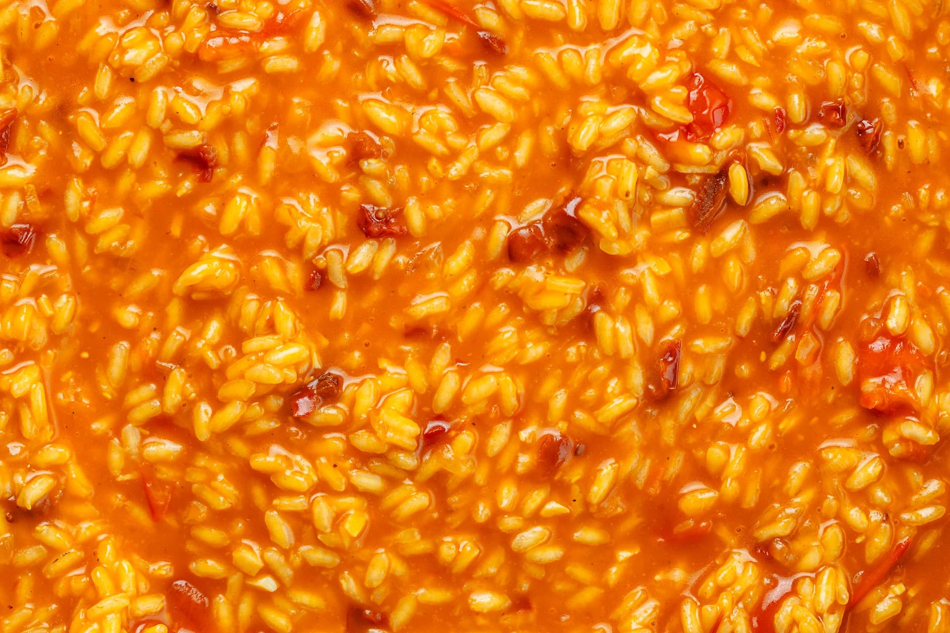 Close-up of creamy tomato risotto showing glossy grains of rice in a rich red sauce.