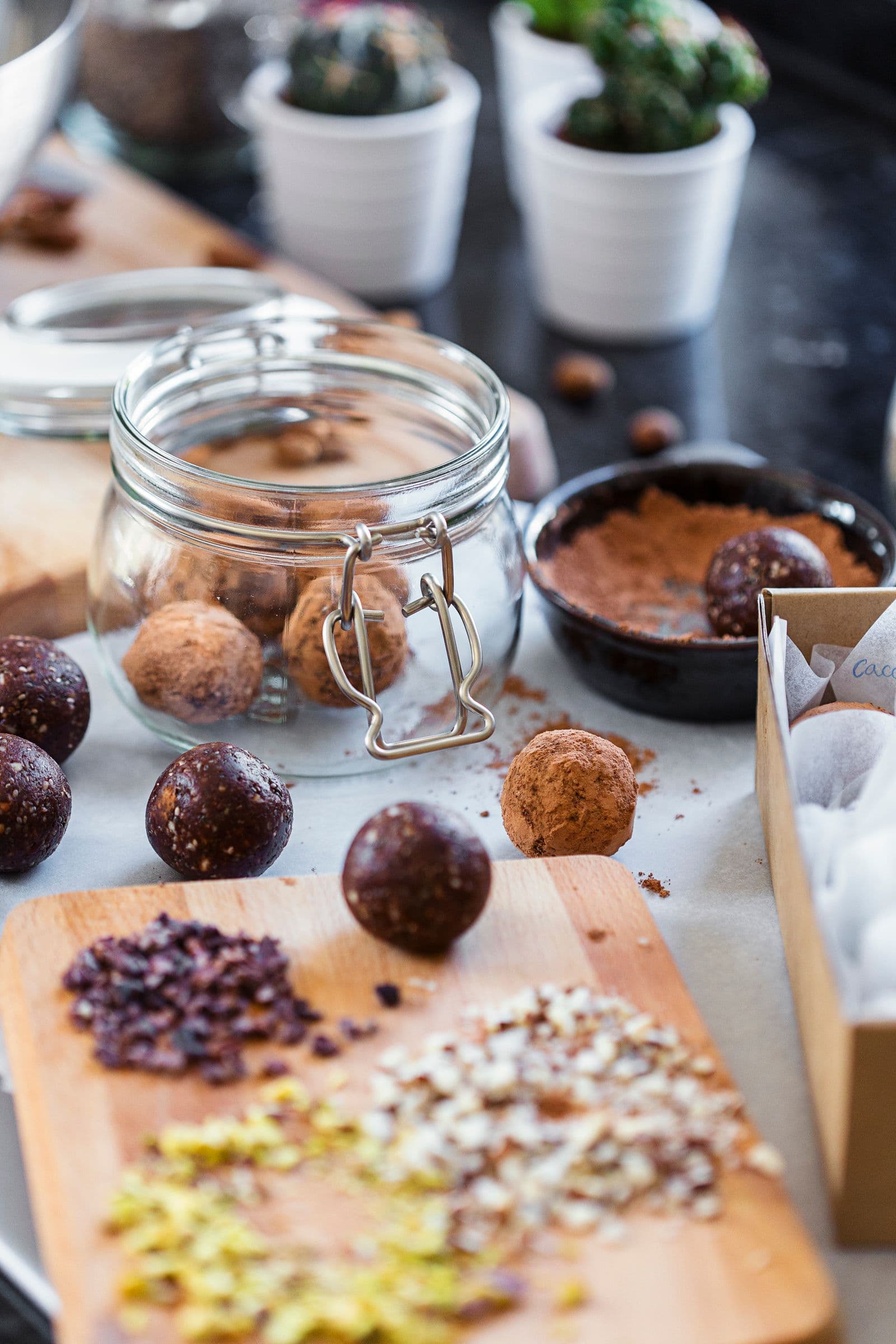 Frasco de vidro e tábua de madeira com bolinhas energéticas e cacau em pó.