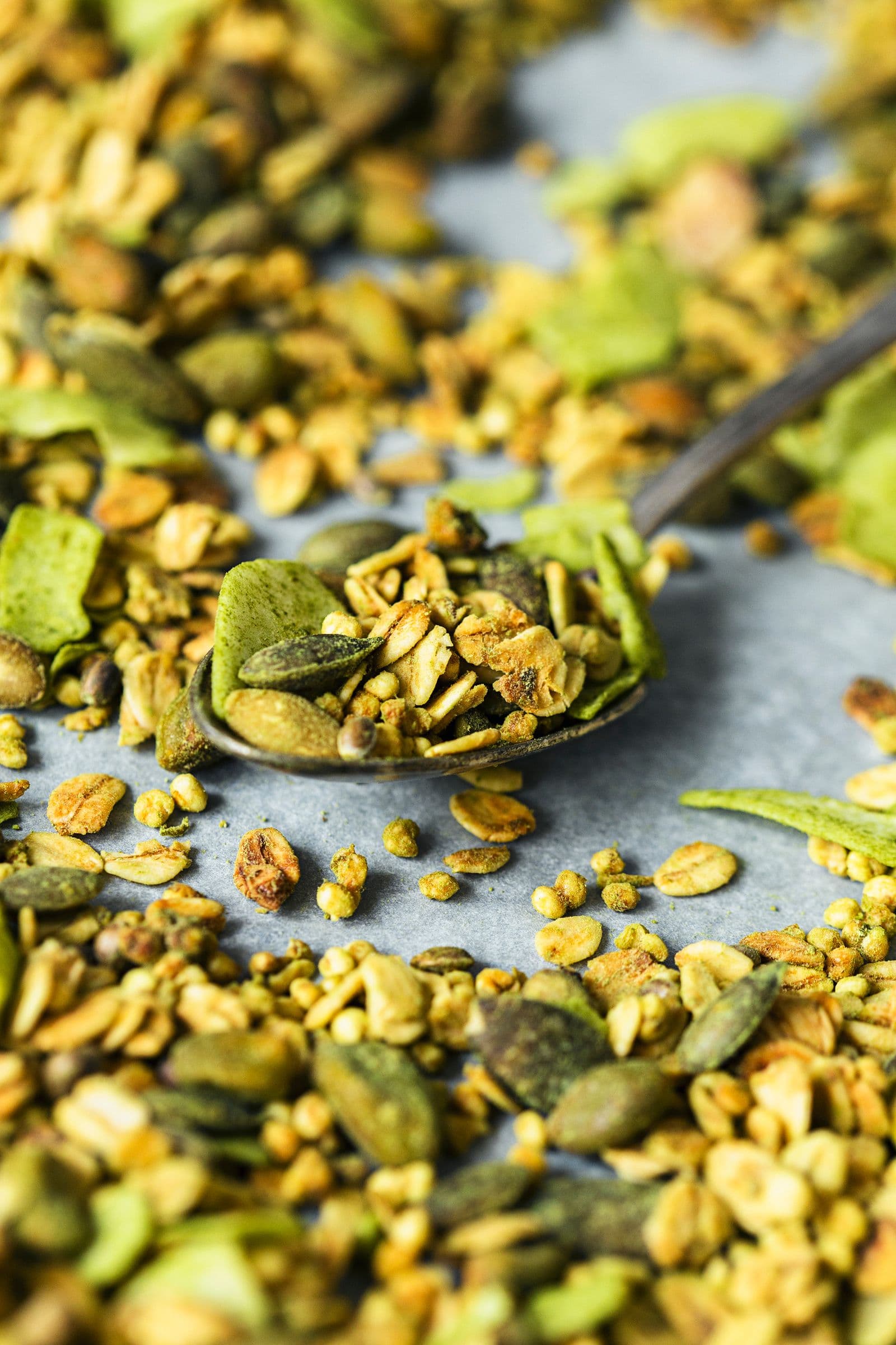 Colher metálica a retirar granola verde superalimento do papel vegetal.