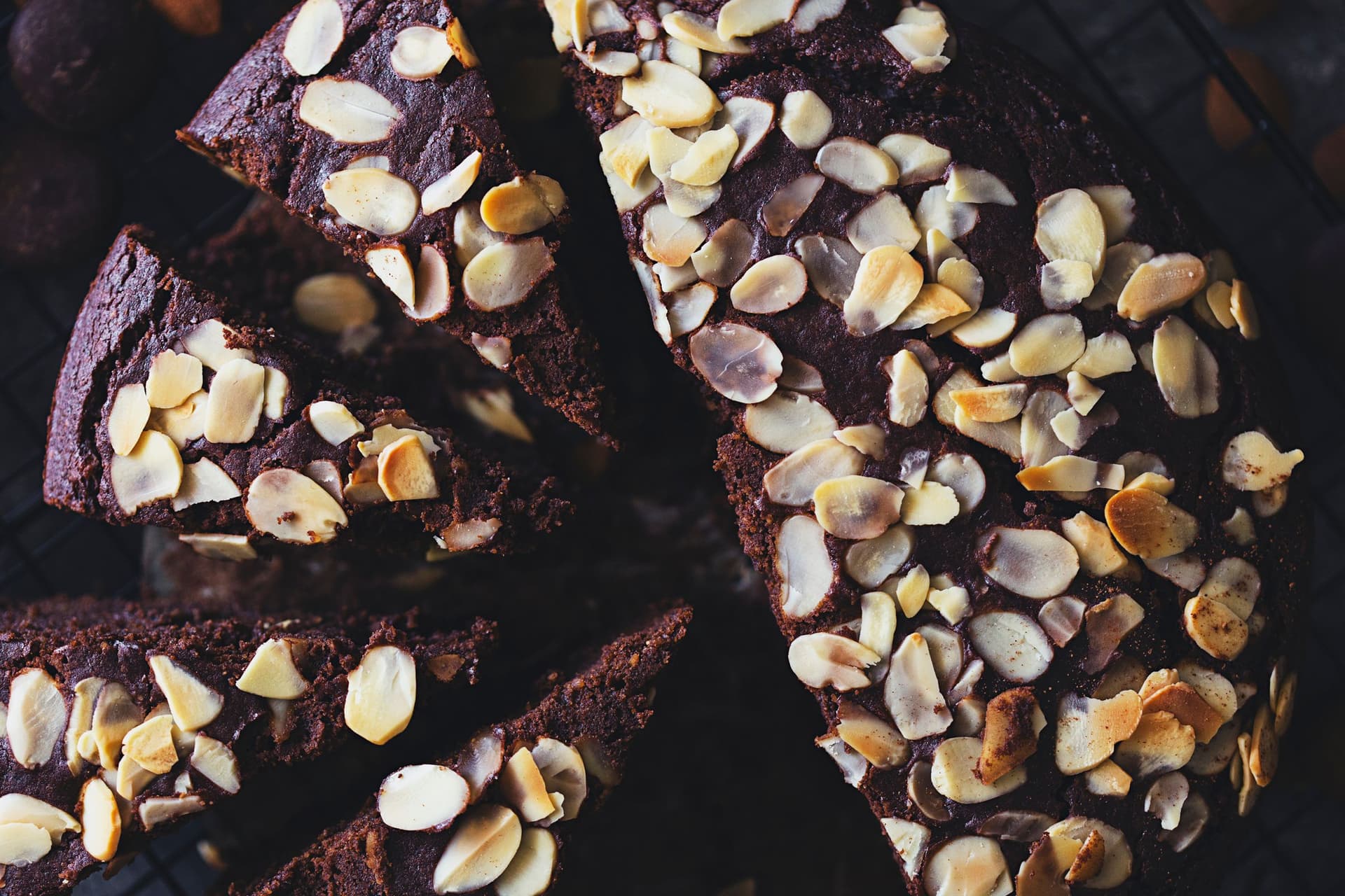 Overhead shot of the cake with a cut slices and scattered almonds.