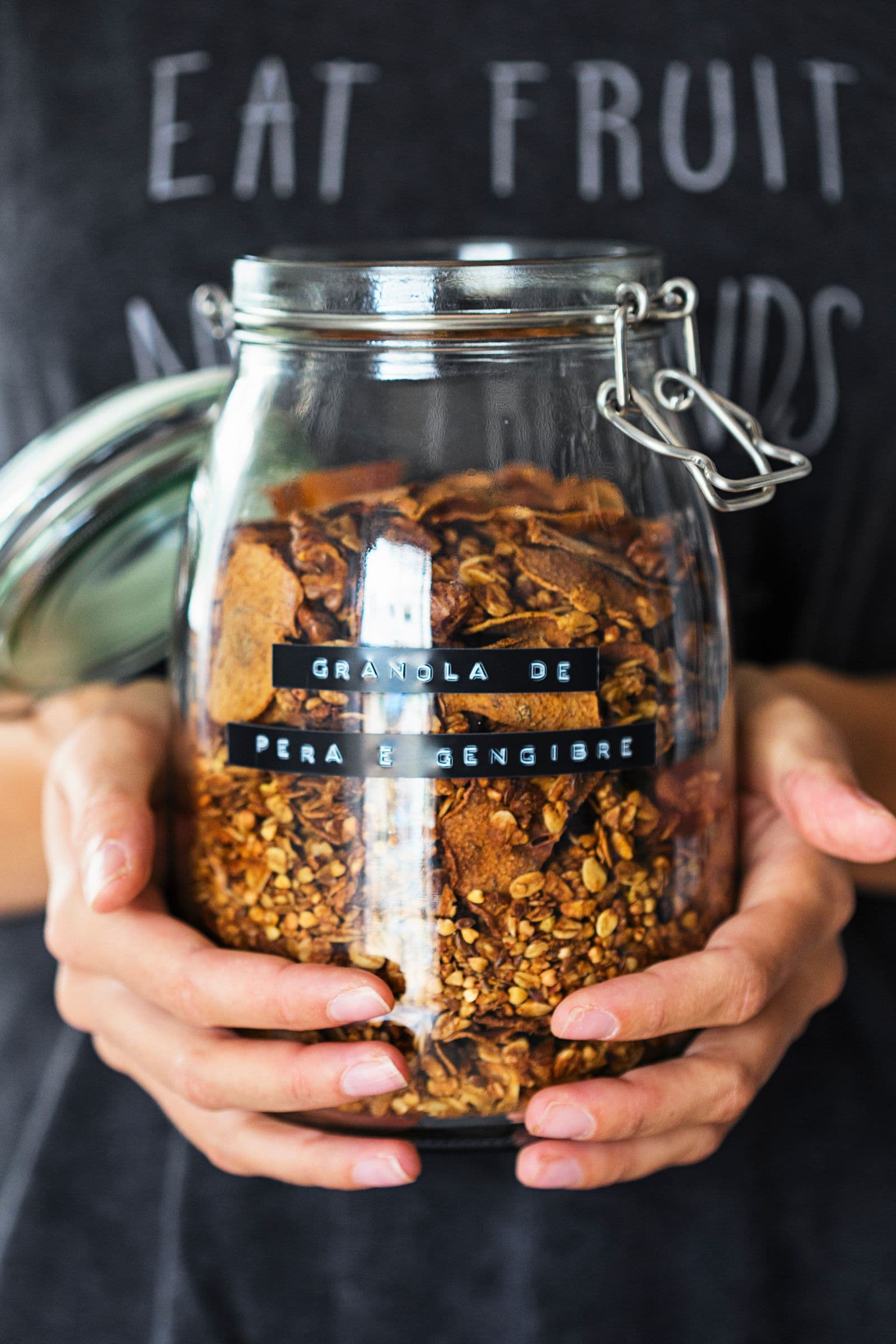 Pessoa a segurar um frasco rotulado de granola de pêra e gengibre.