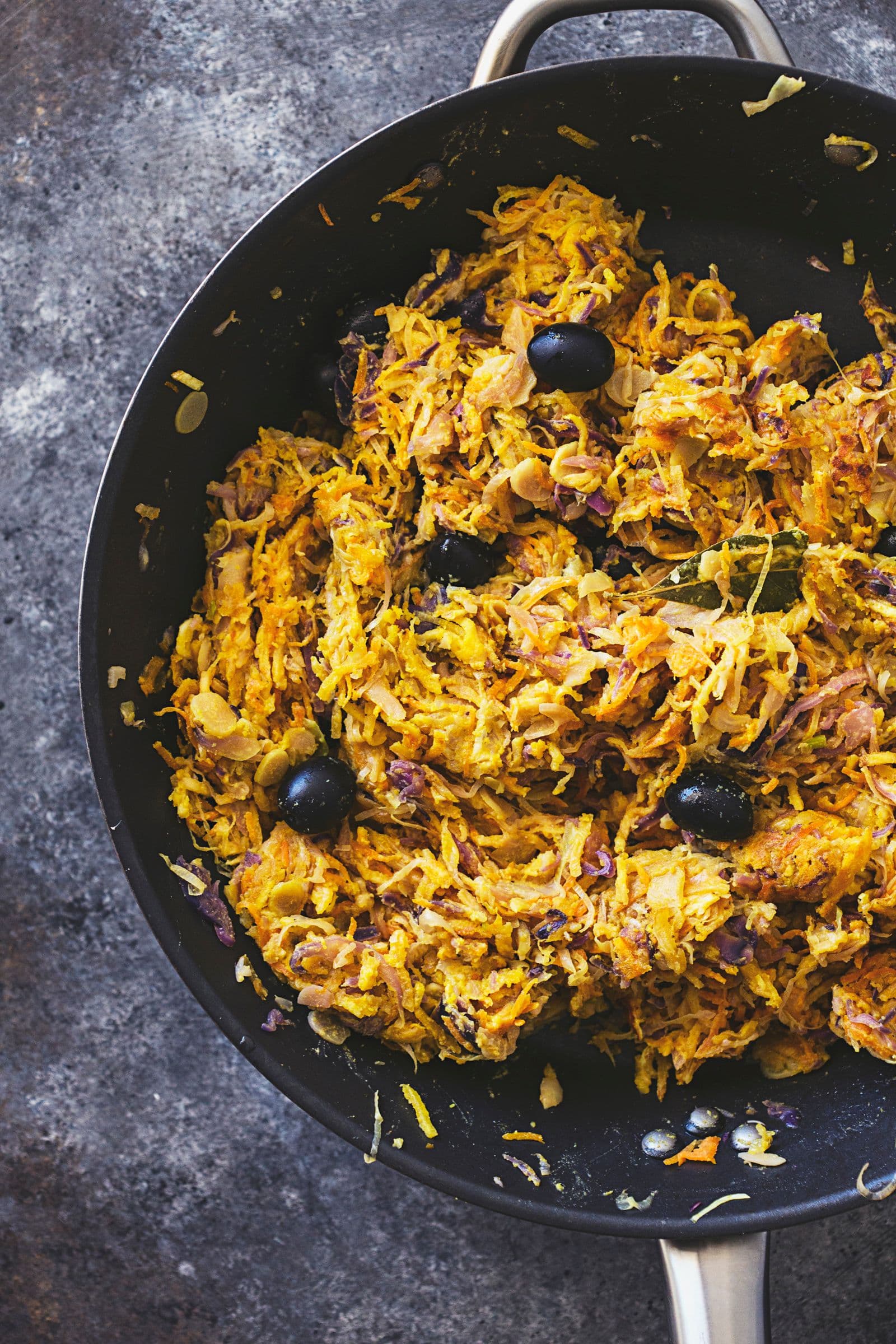 Portuguese veggie hash dotted with black olives, ready to serve.