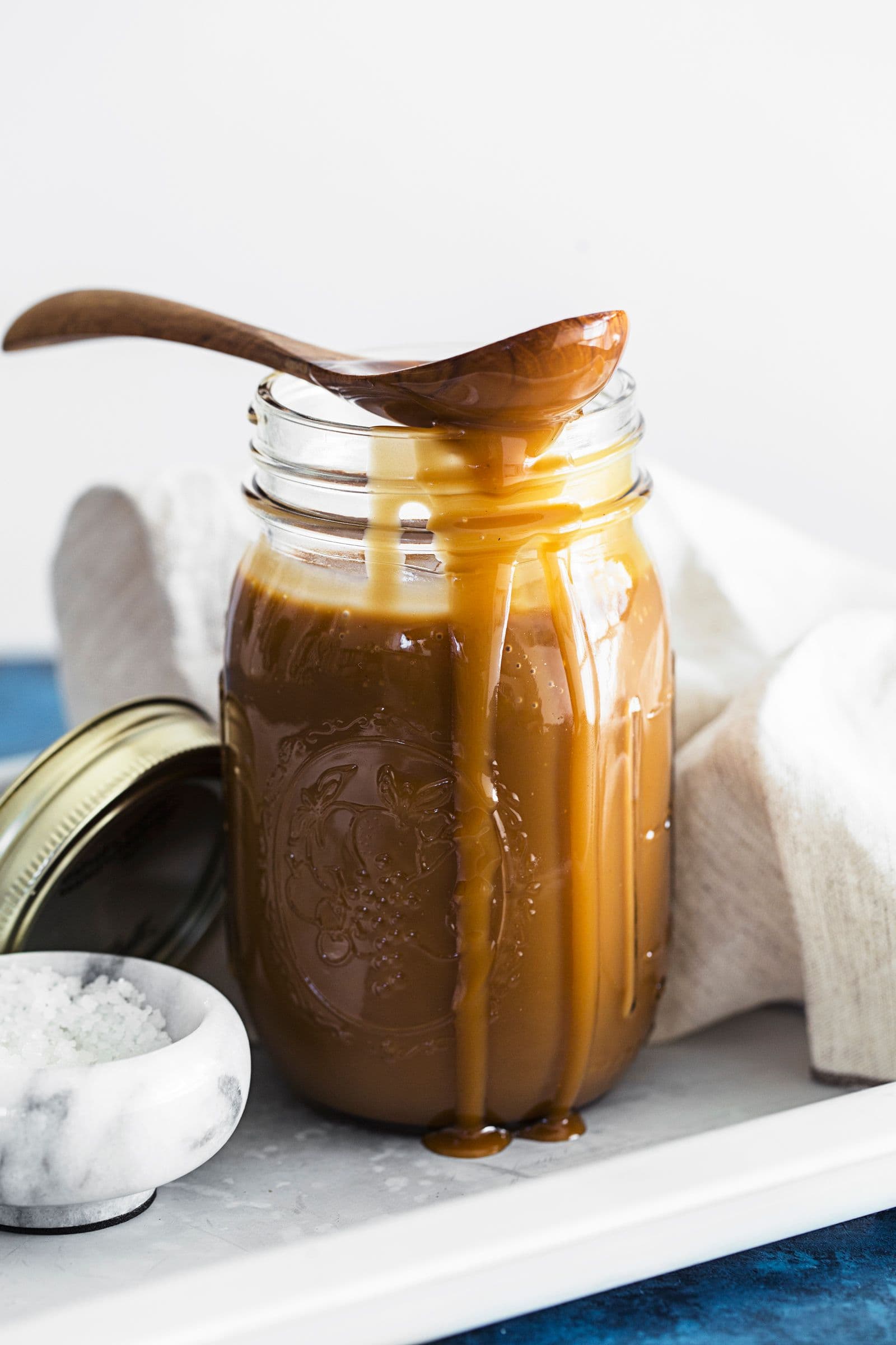Glass jar with vegan coconut salted caramel dripping down the sides.