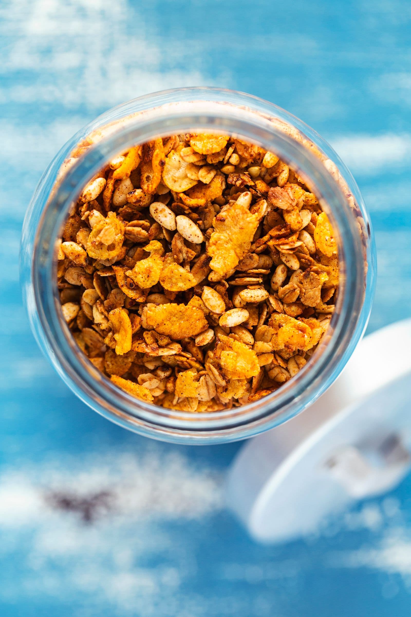 Vista de cima de granola crocante com cornflakes dentro de um frasco aberto.