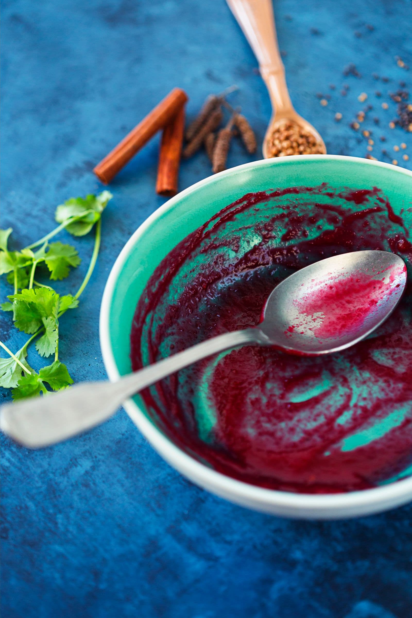 Nearly empty bowl showing the last streaks of beetroot soup with a spoon resting inside.