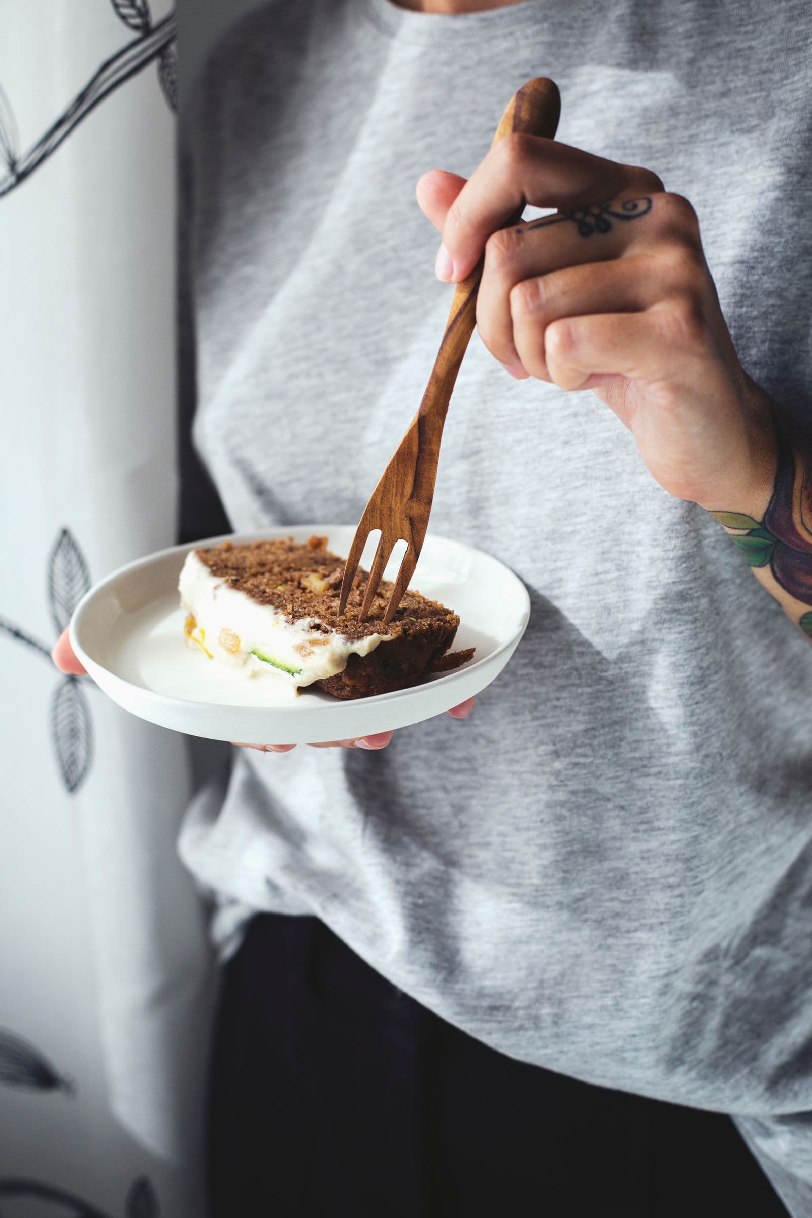 Mão a segurar um garfo com um pedaço de bolo de curgete e limão.