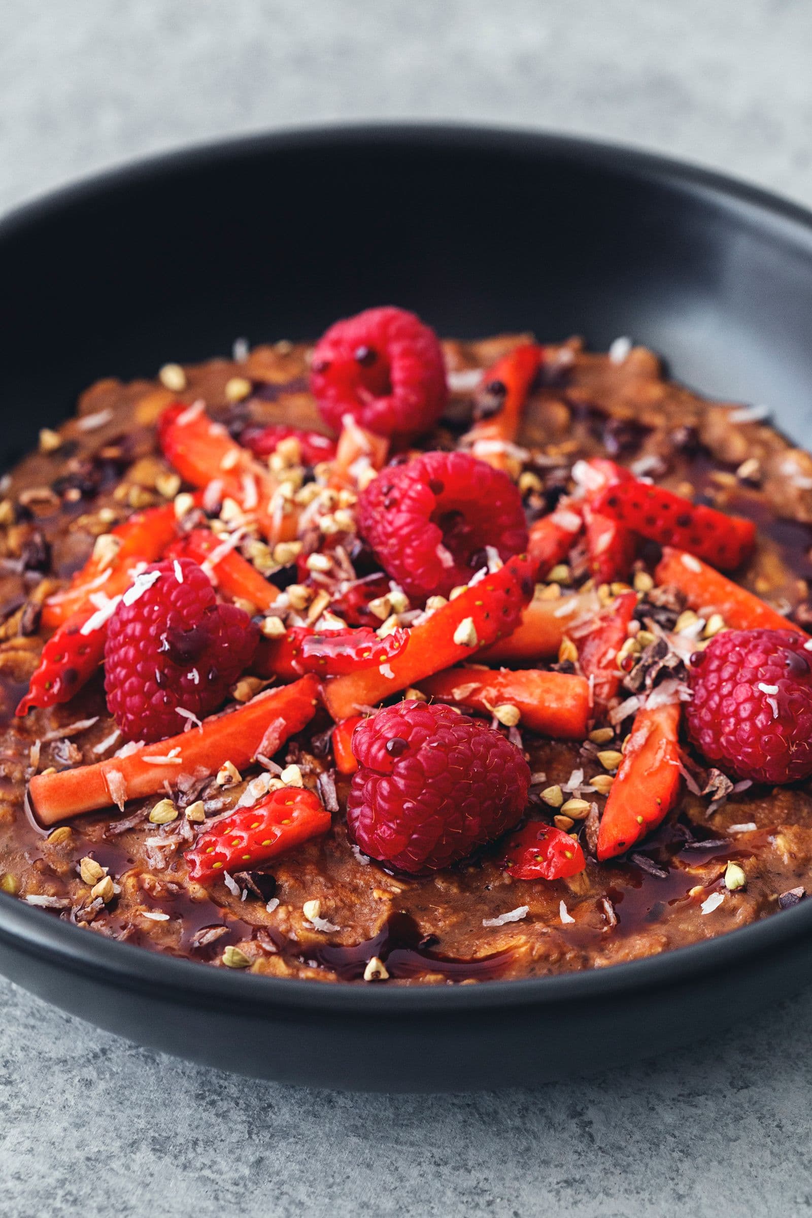 Bowl of cacao oatmeal with raspberries and strawberries, ready to eat.