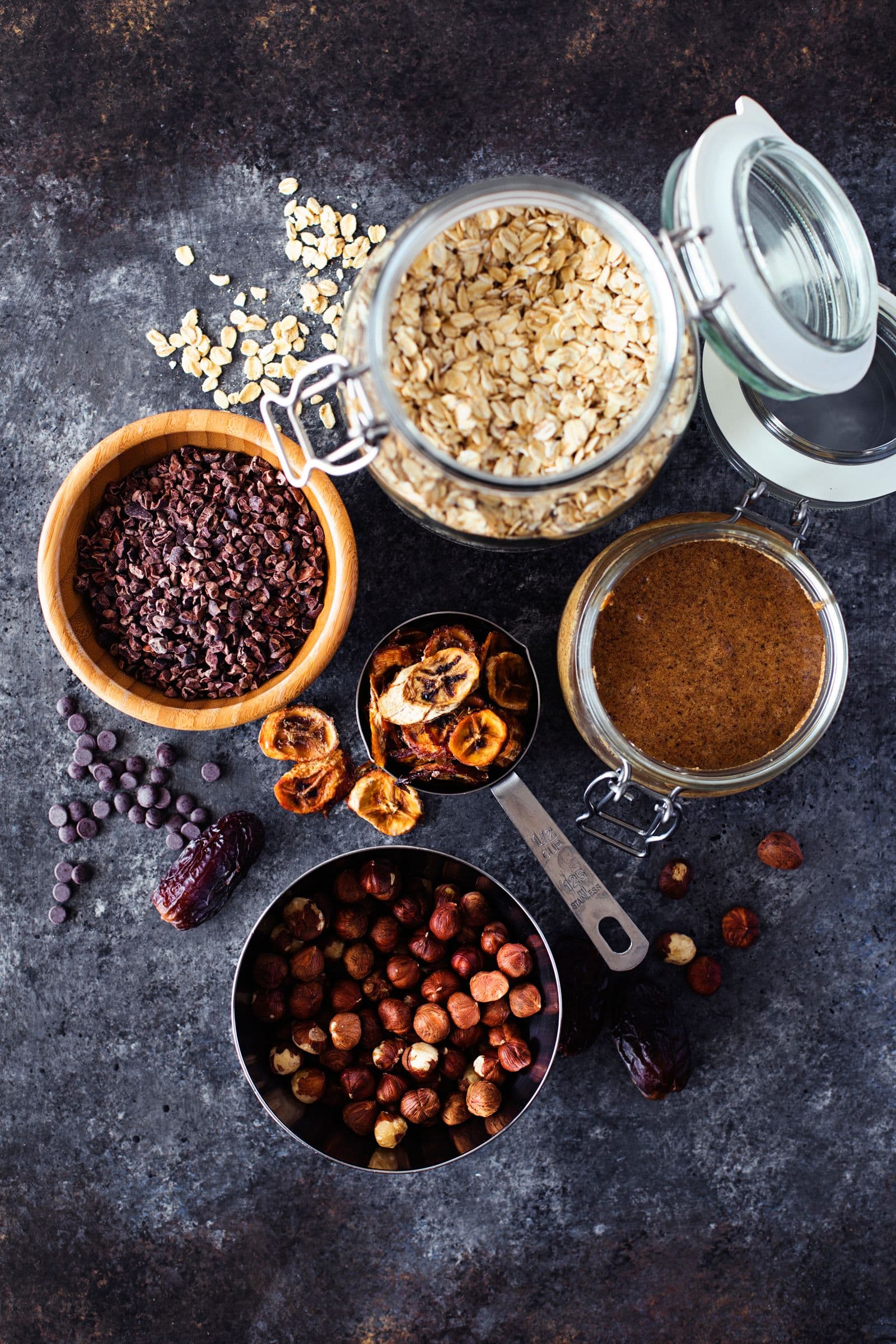 Overhead of oats, cacao nibs and other ingredients in glass jars.