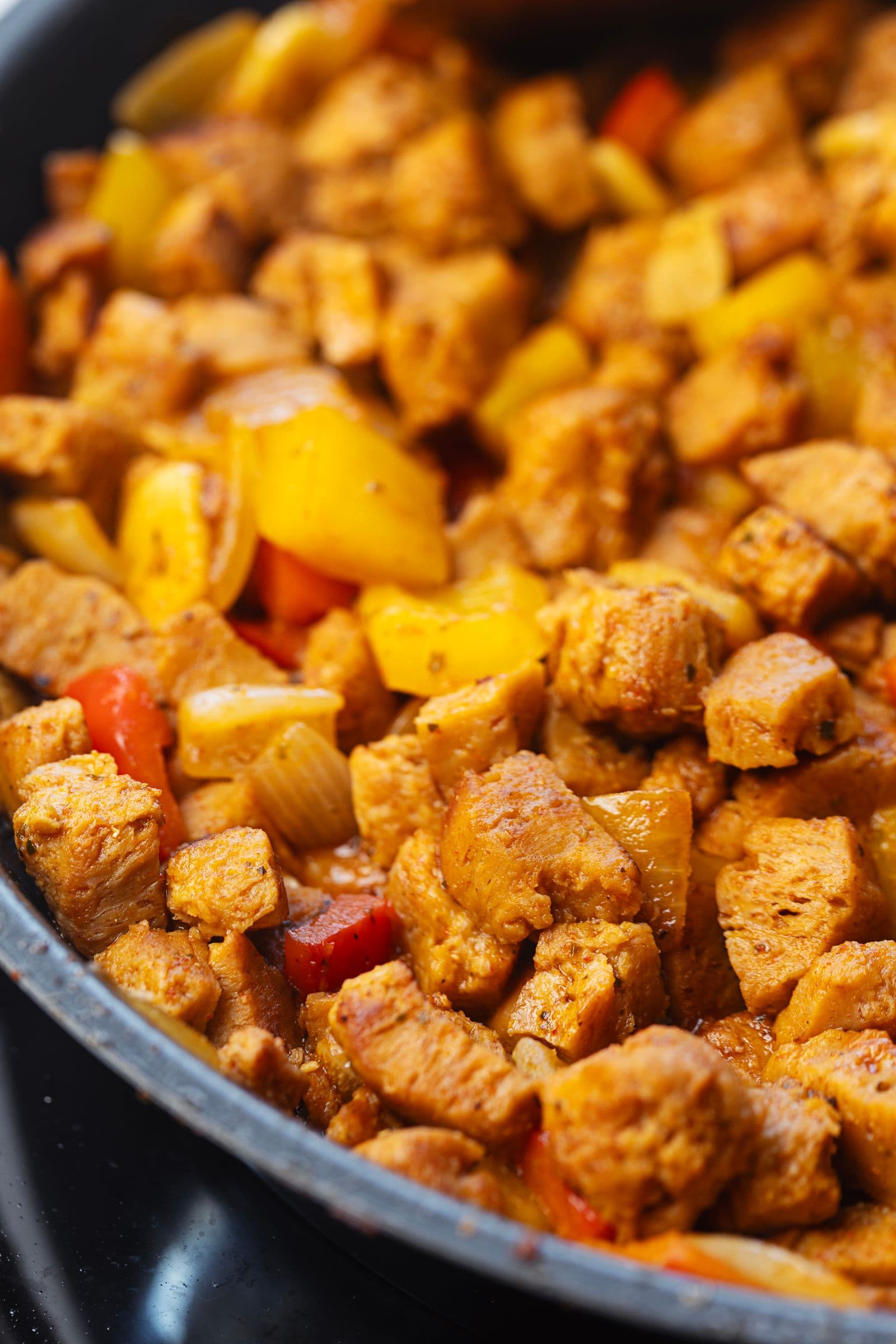 Nacos de soja salteados com pimentos amarelos e vermelhos numa frigideira, durante a cozedura do pica pau de soja