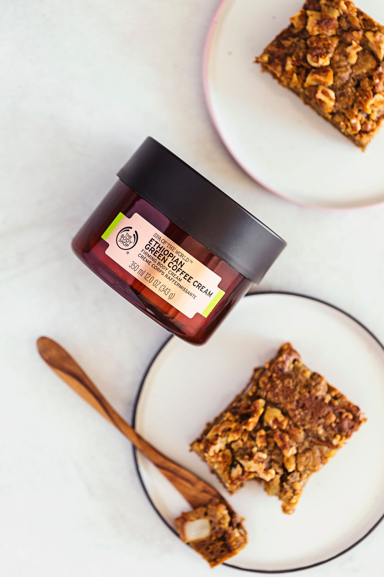 Vegan coffee cake slice next to a jar of coffee cream, styled on a white background.