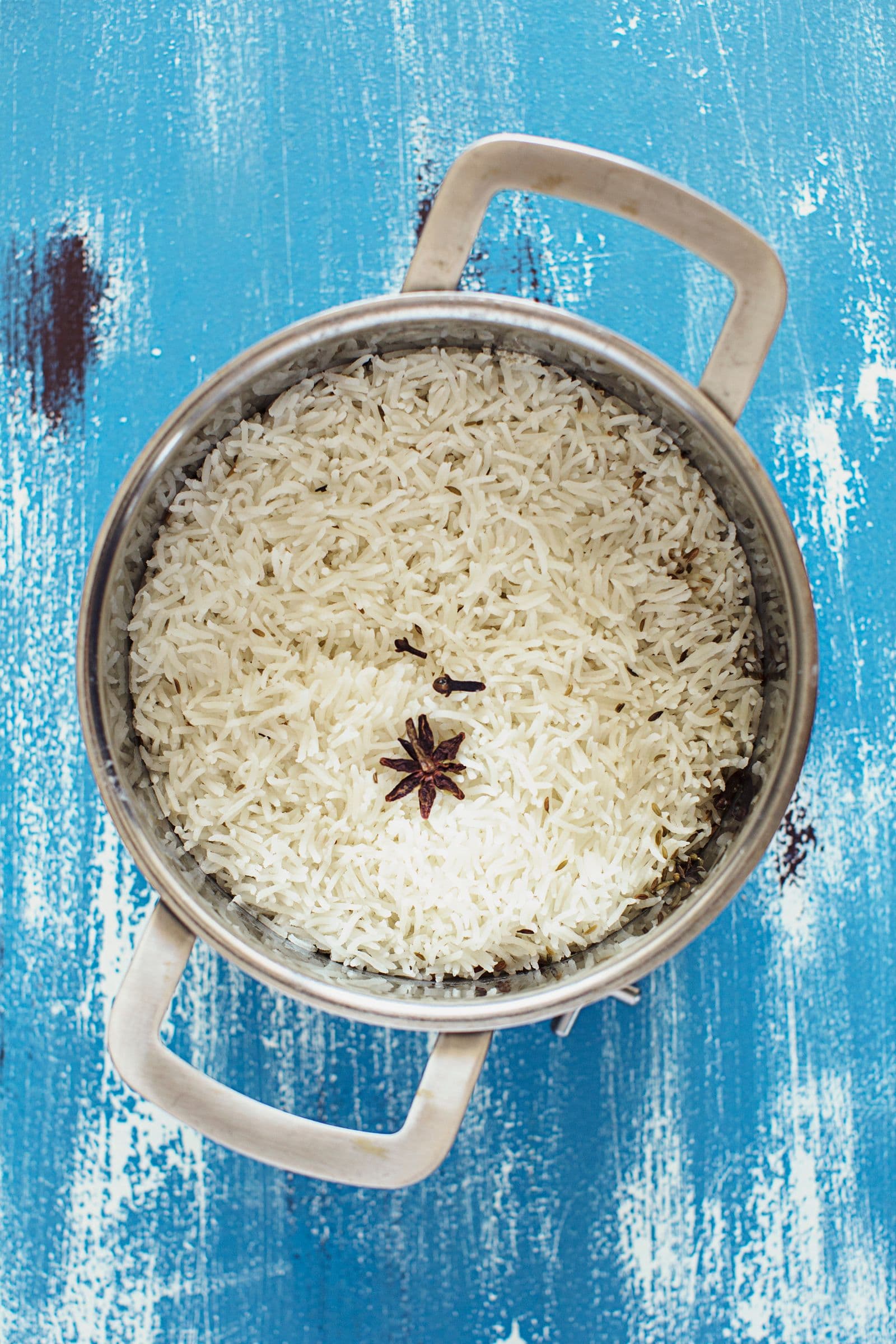 Vista de cima de panela com arroz basmati cozinhado e anis-estrelado no topo.