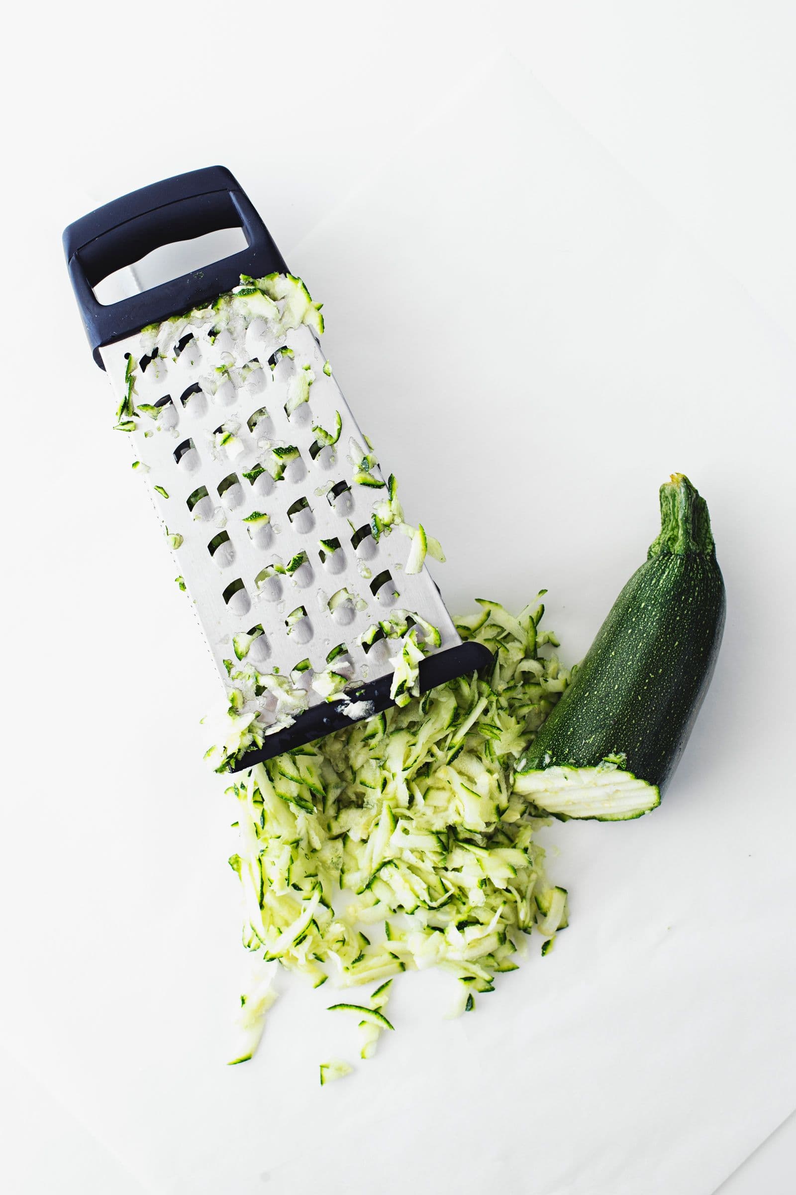 Fresh zucchini being grated on a box grater for the cake batter.