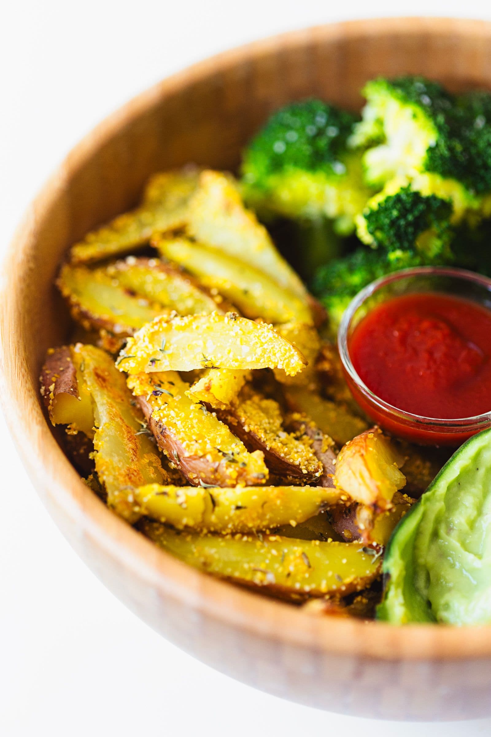 Taça com batata assada, brócolos ao vapor, guacamole cremoso e ketchup.