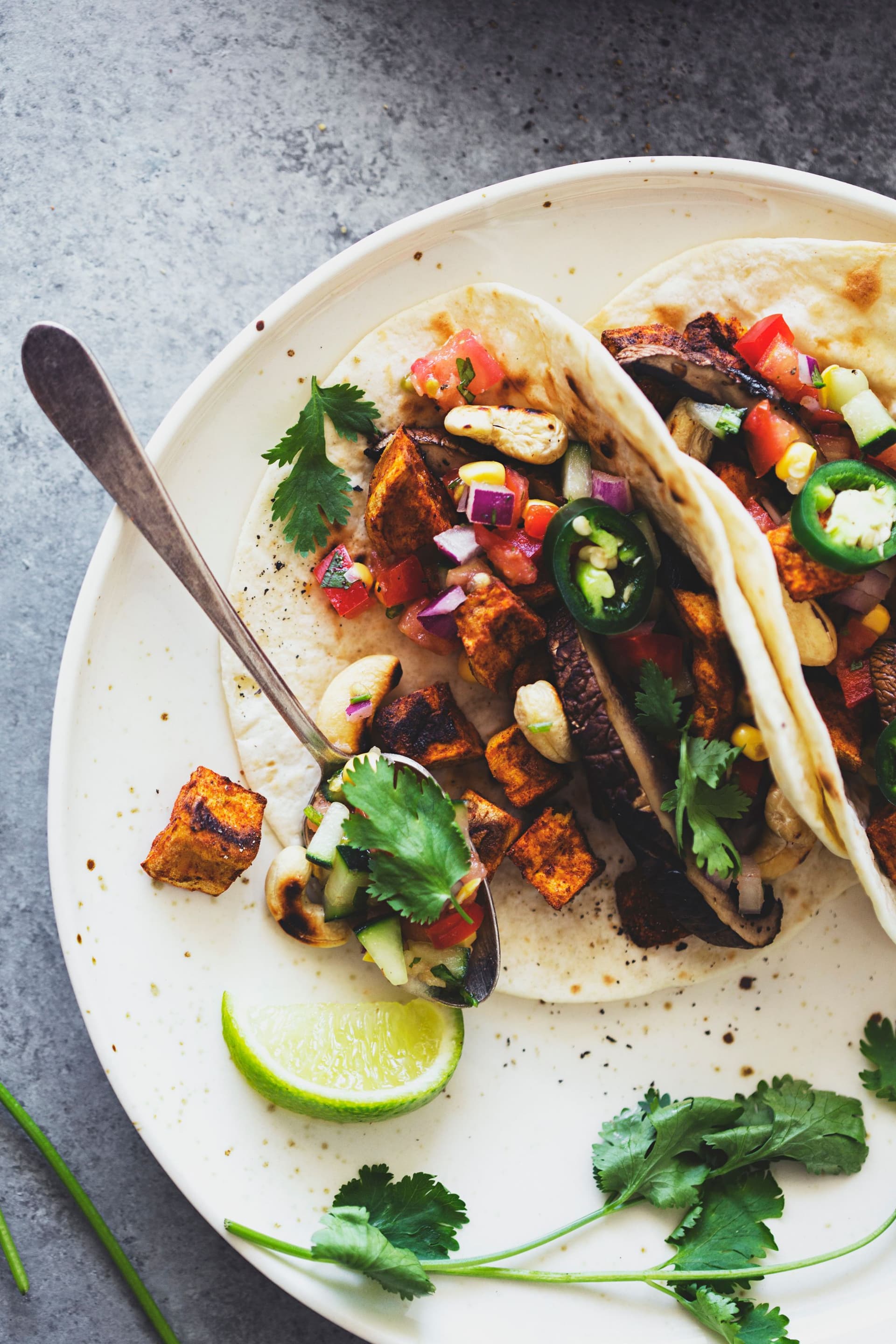 Two tacos on a plate with salsa and fresh coriander.
