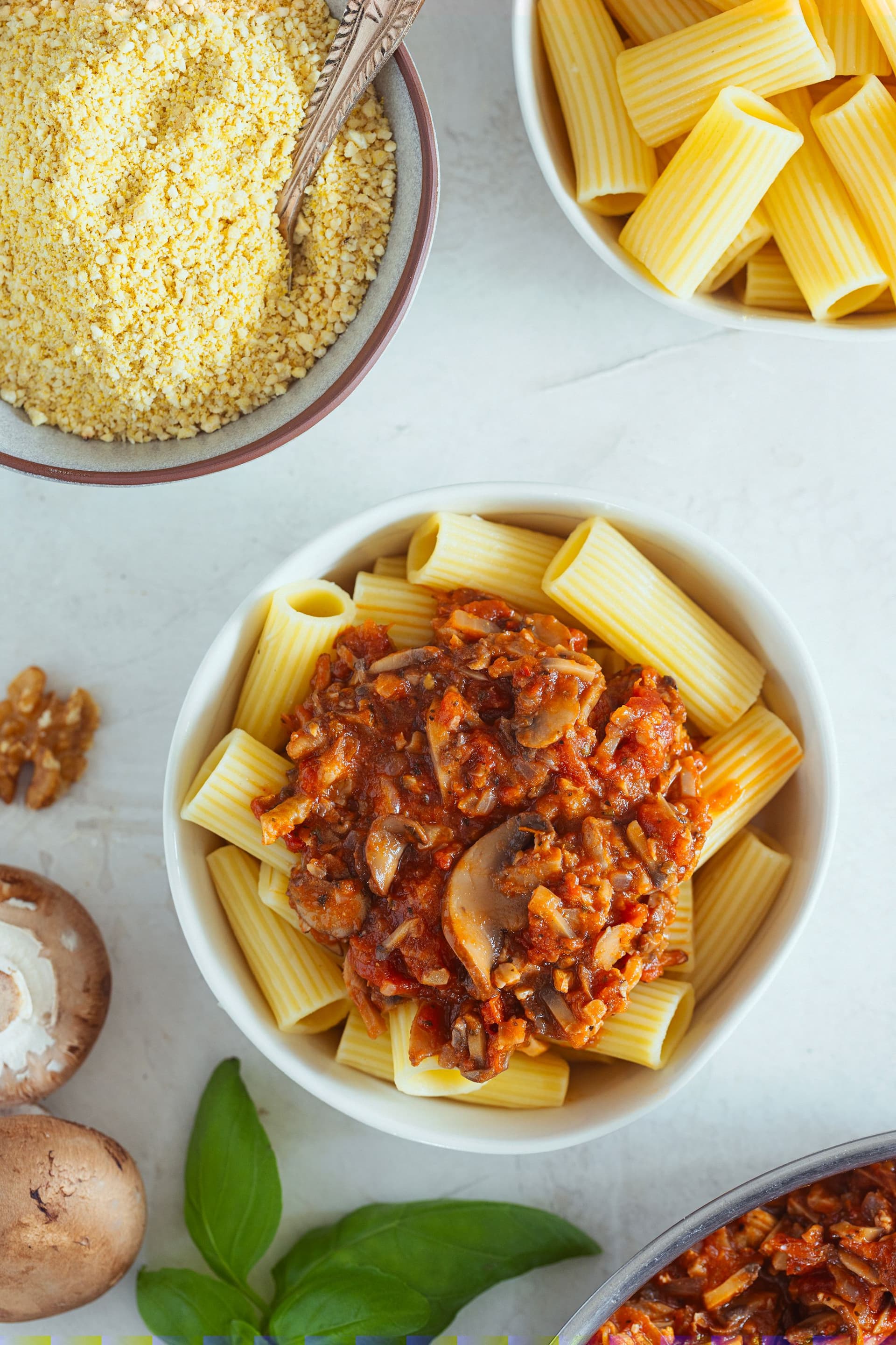 Rigatoni and vegan parmesan laid out while assembling the dish.