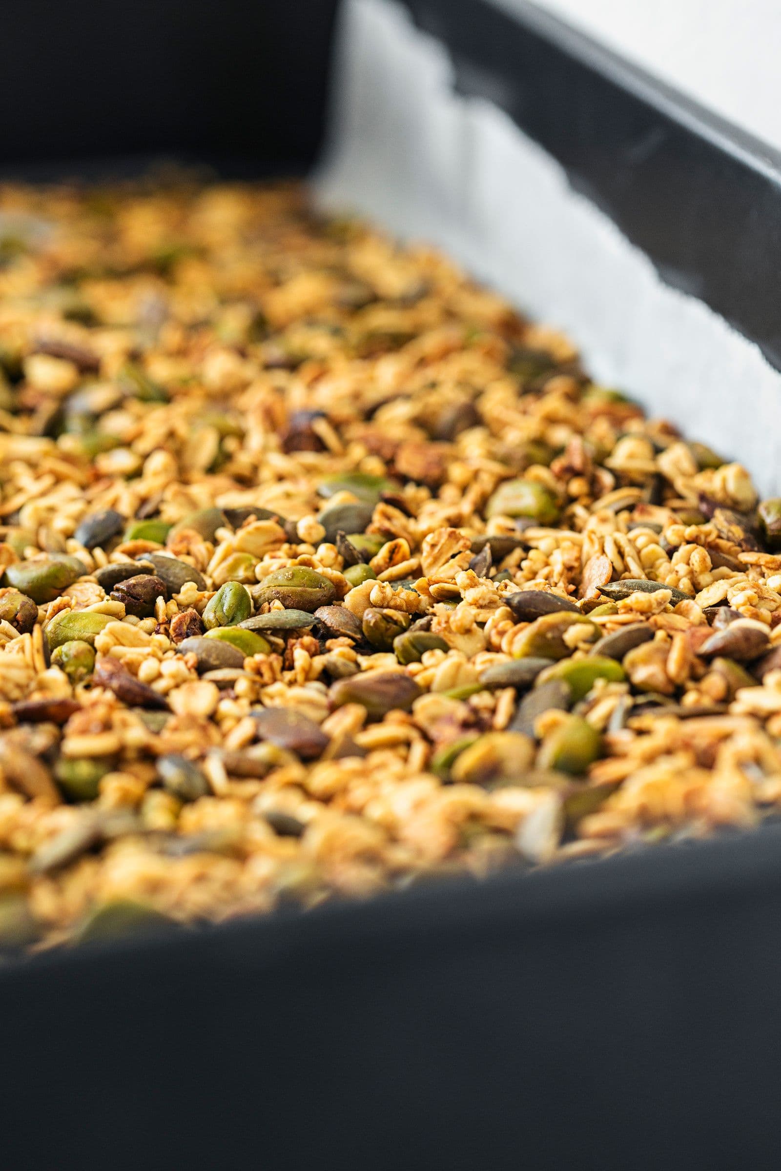 Granola acabada de sair do forno com tom dourado, ainda no tabuleiro.