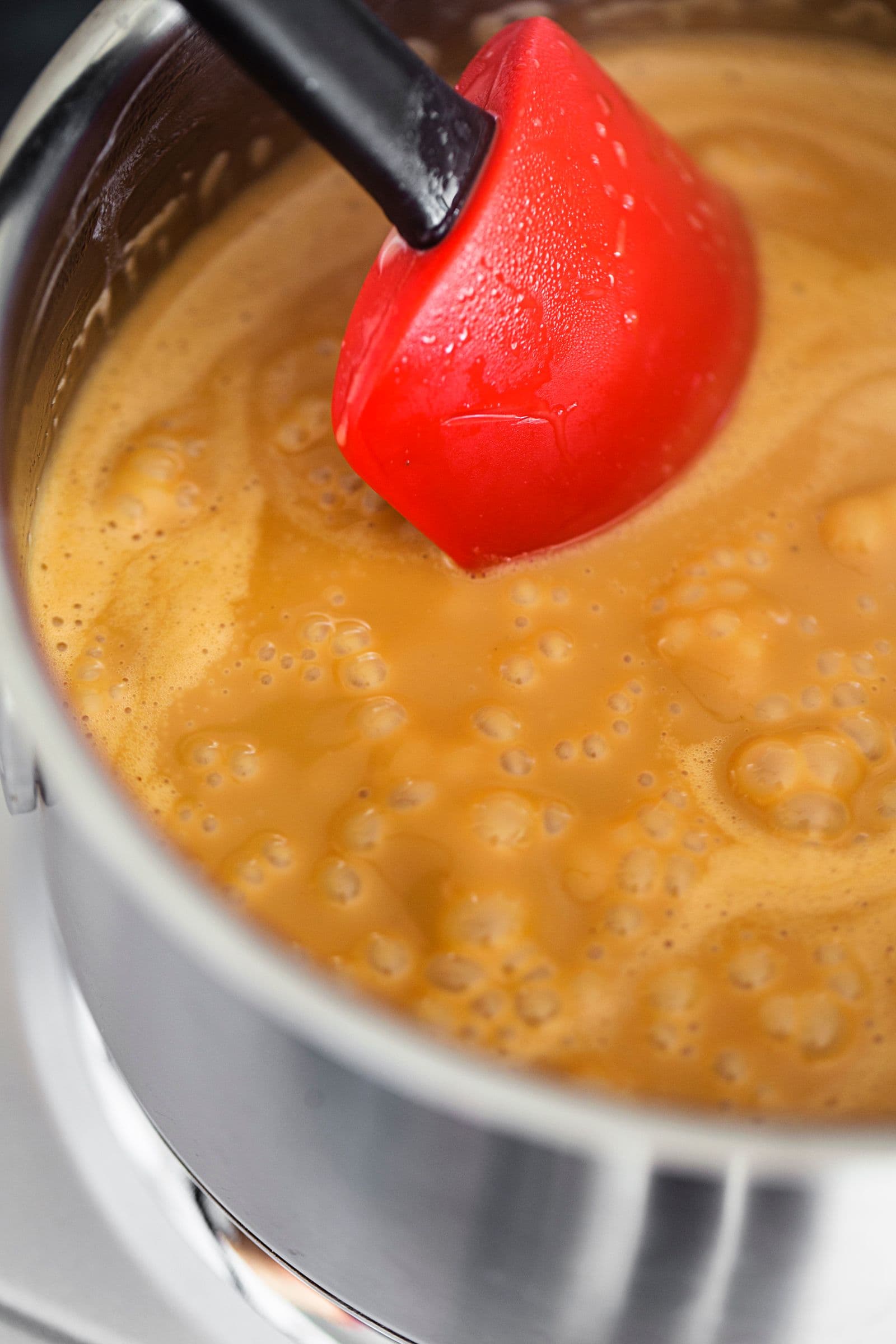 Mistura de leite de coco e açúcar a engrossar durante a preparação do caramelo.