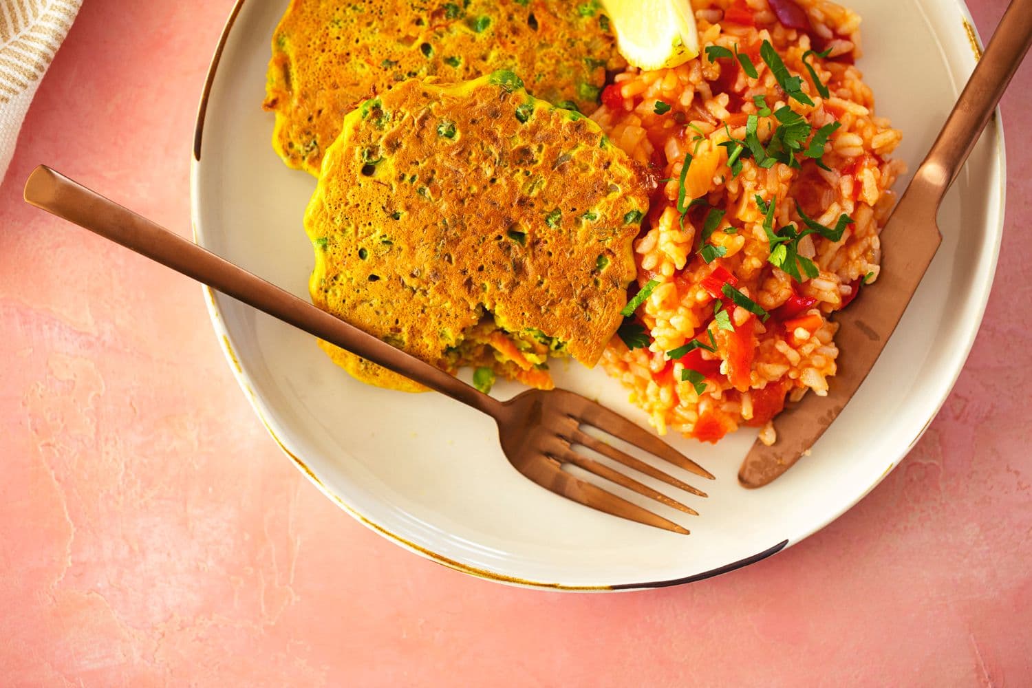 Prato servido com duas pataniscas de grão-de-bico e legumes, acompanhados de arroz malandrinho de tomate