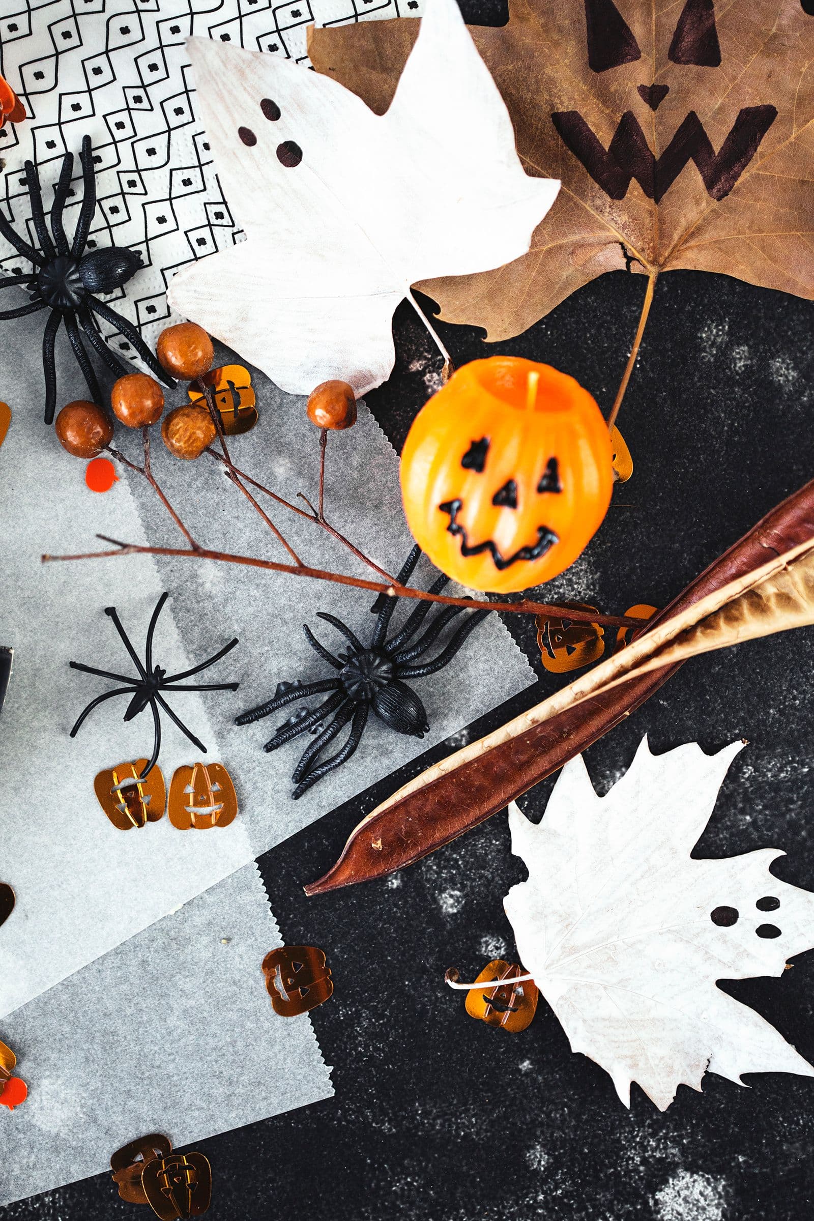 Dessert table set with cheesecake slices, autumn leaves and a pumpkin-shaped candle.