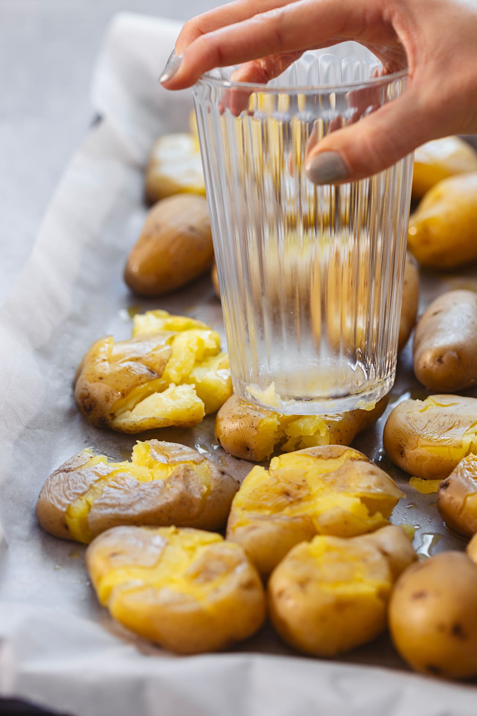 Smashed baby potatoes in progress, using a glass for pressing