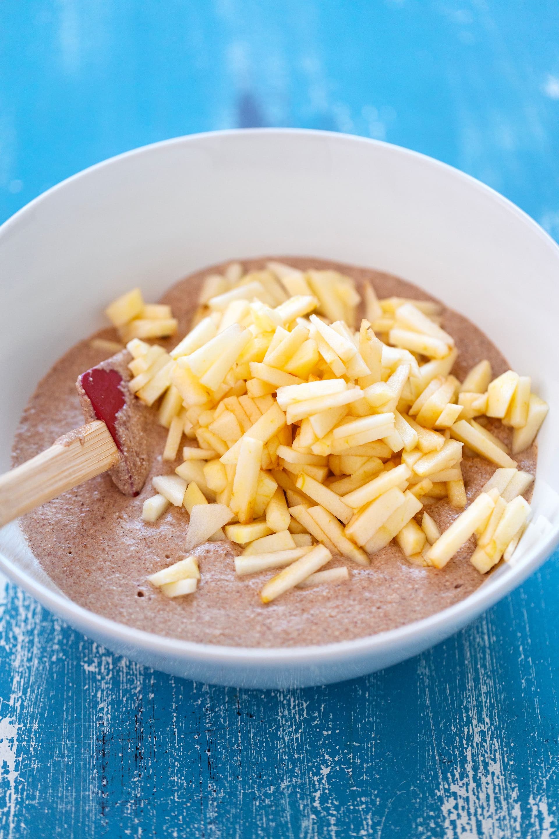 Massa das panquecas numa taça com maçã picada antes de misturar.