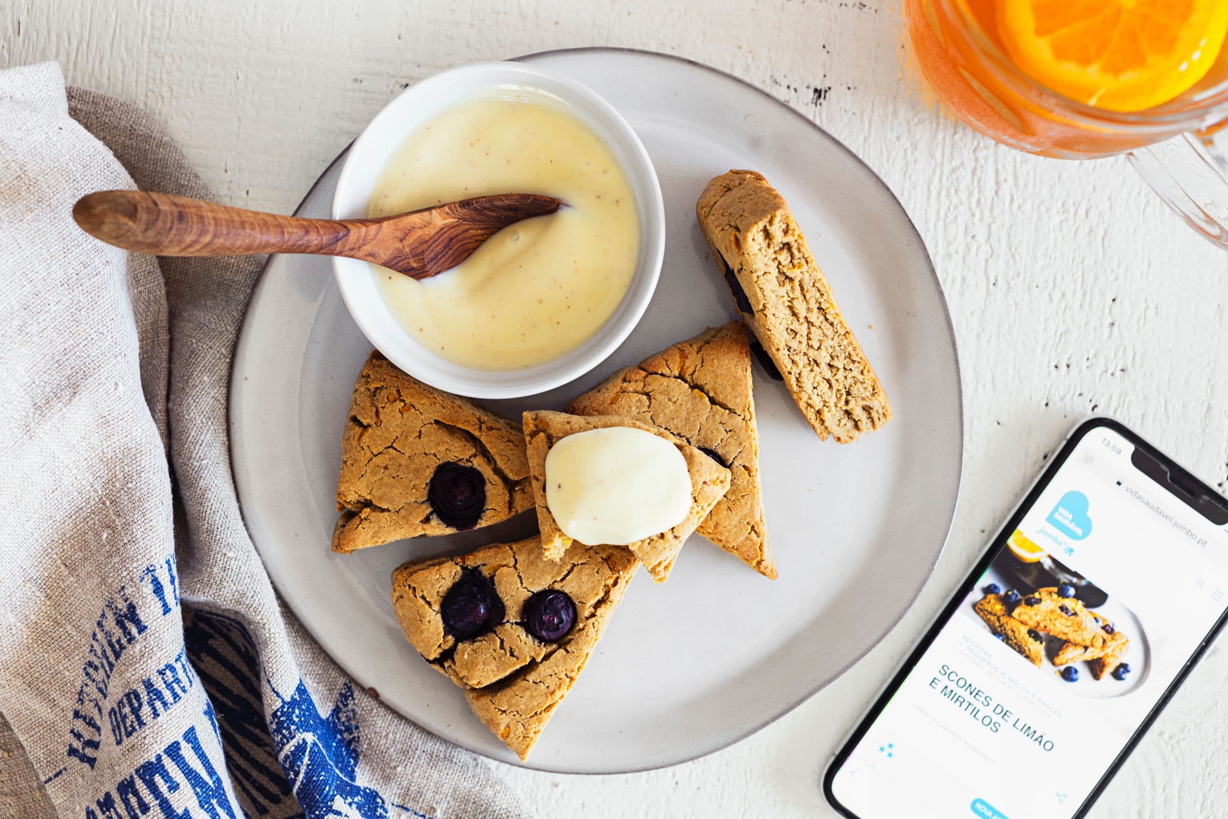 Vegan lemon and blueberry scones served with cream on a plate.