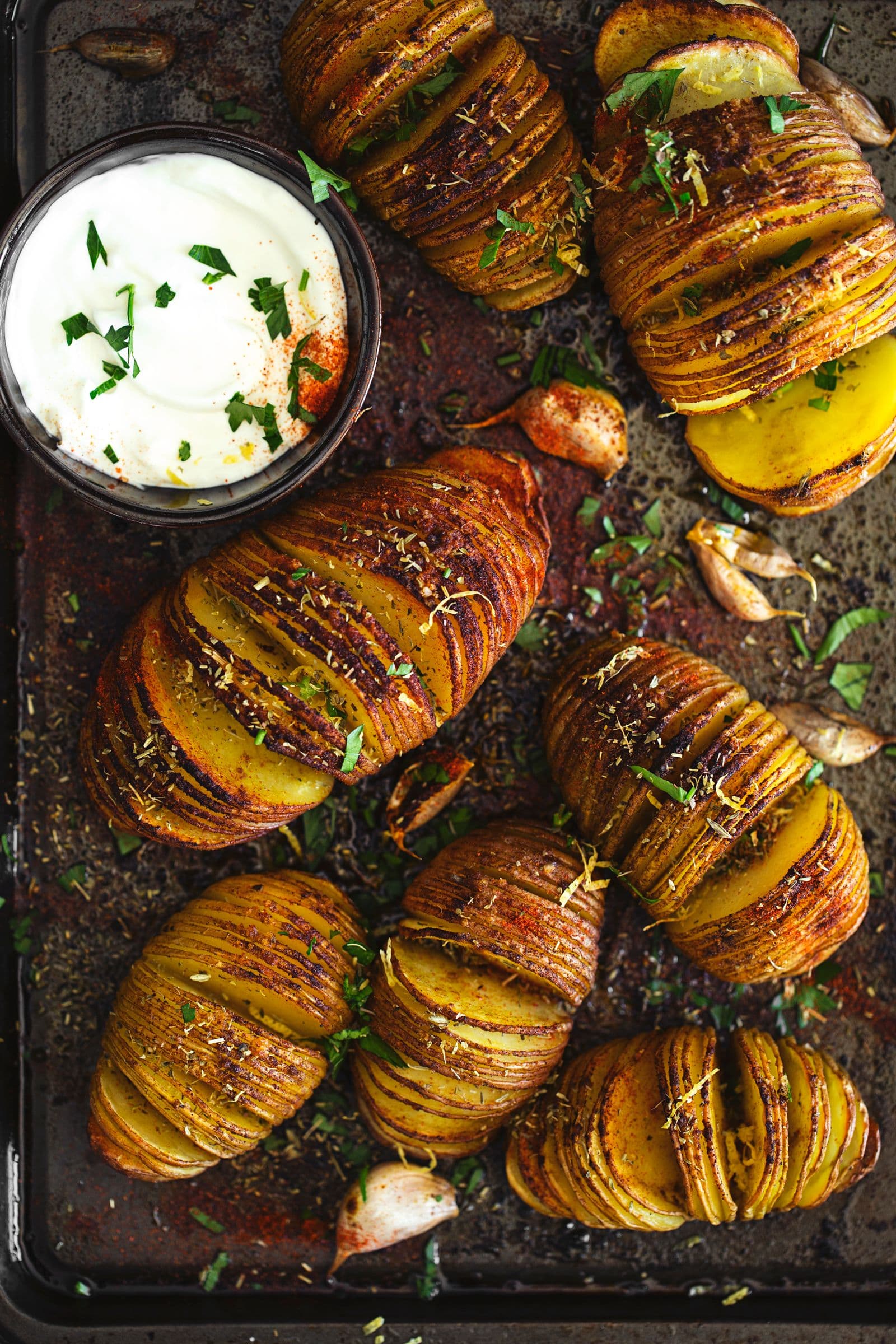 Baking tray with beautifully baked Hasselback potatoes and a ramekin of plant-based mayo.